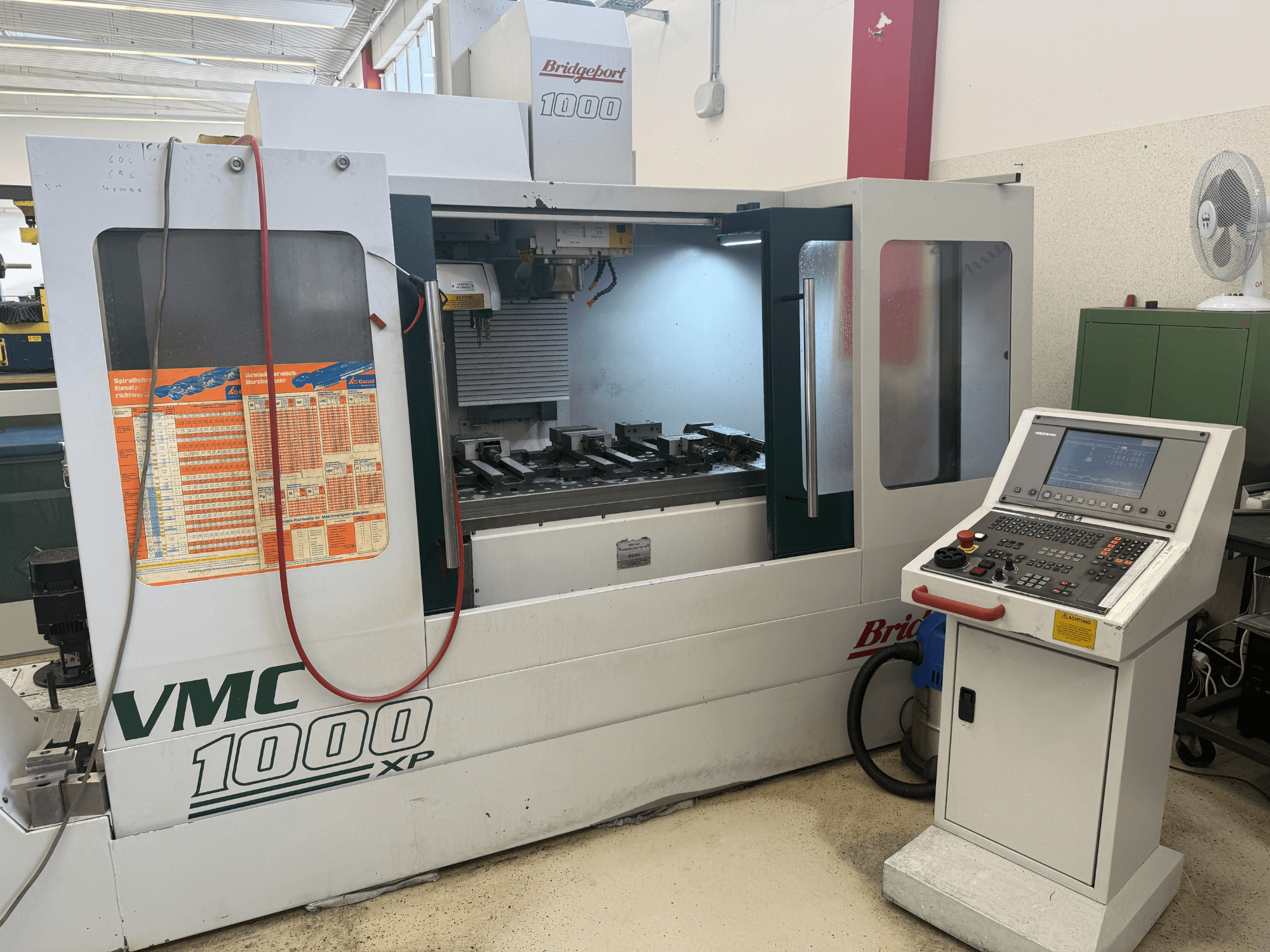 Вигляд спереду вертикального обробного центру Bridgeport VMC 1000 XP, на якому видно органи управління, робочу зону та кріплення інструментів.