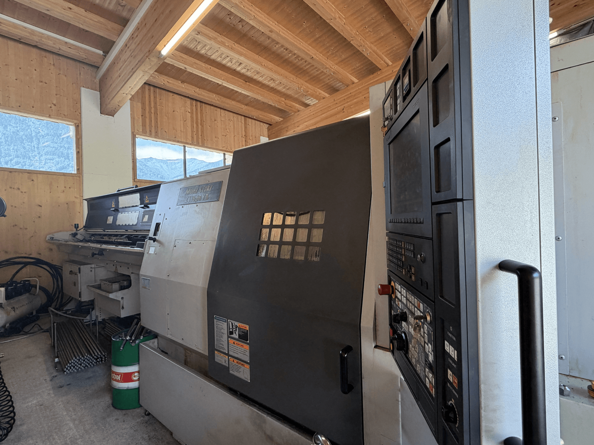 Токарно-фрезерний центр MORI SEIKI ZT1500YB у цеху, вид збоку, на якому видно панель управління та особливості верстата.