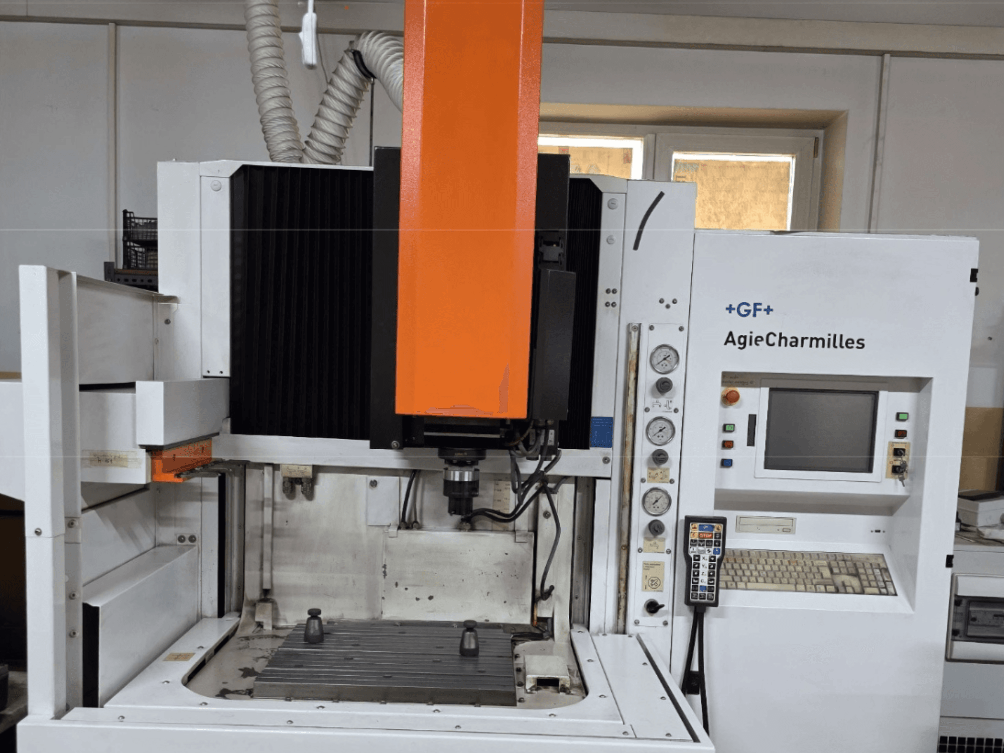 Обробний центр AgieCharmilles спереду з великим помаранчевим шпинделем, панеллю керування та видимим робочим столом.