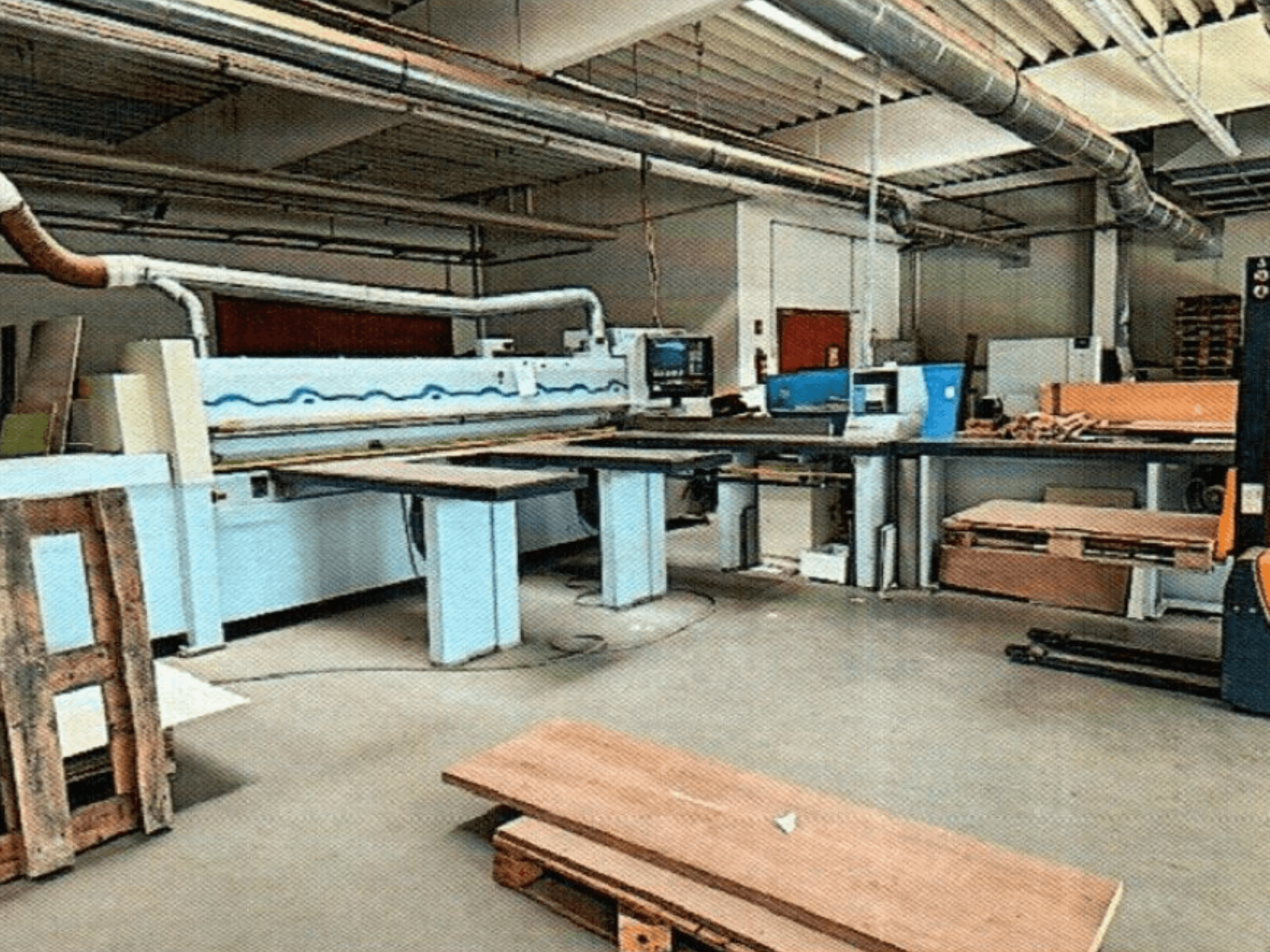 Панельна пила HOMAG HPL 11/38/22 в майстерні з великим розкрійним столом і консоллю дисплея, вид спереду.