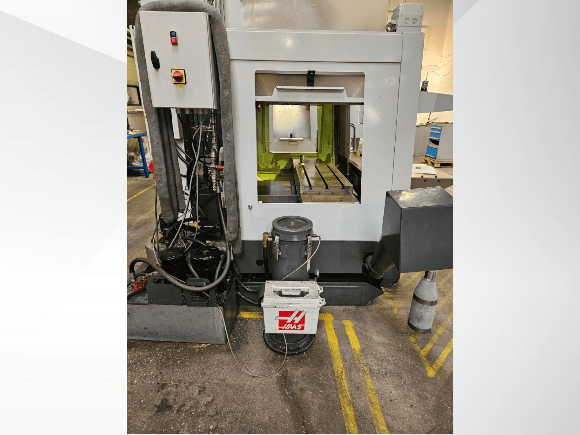 Вид спереду верстата з ЧПК Haas з панеллю керування, баком для охолоджувальної рідини та обробленою станиною.