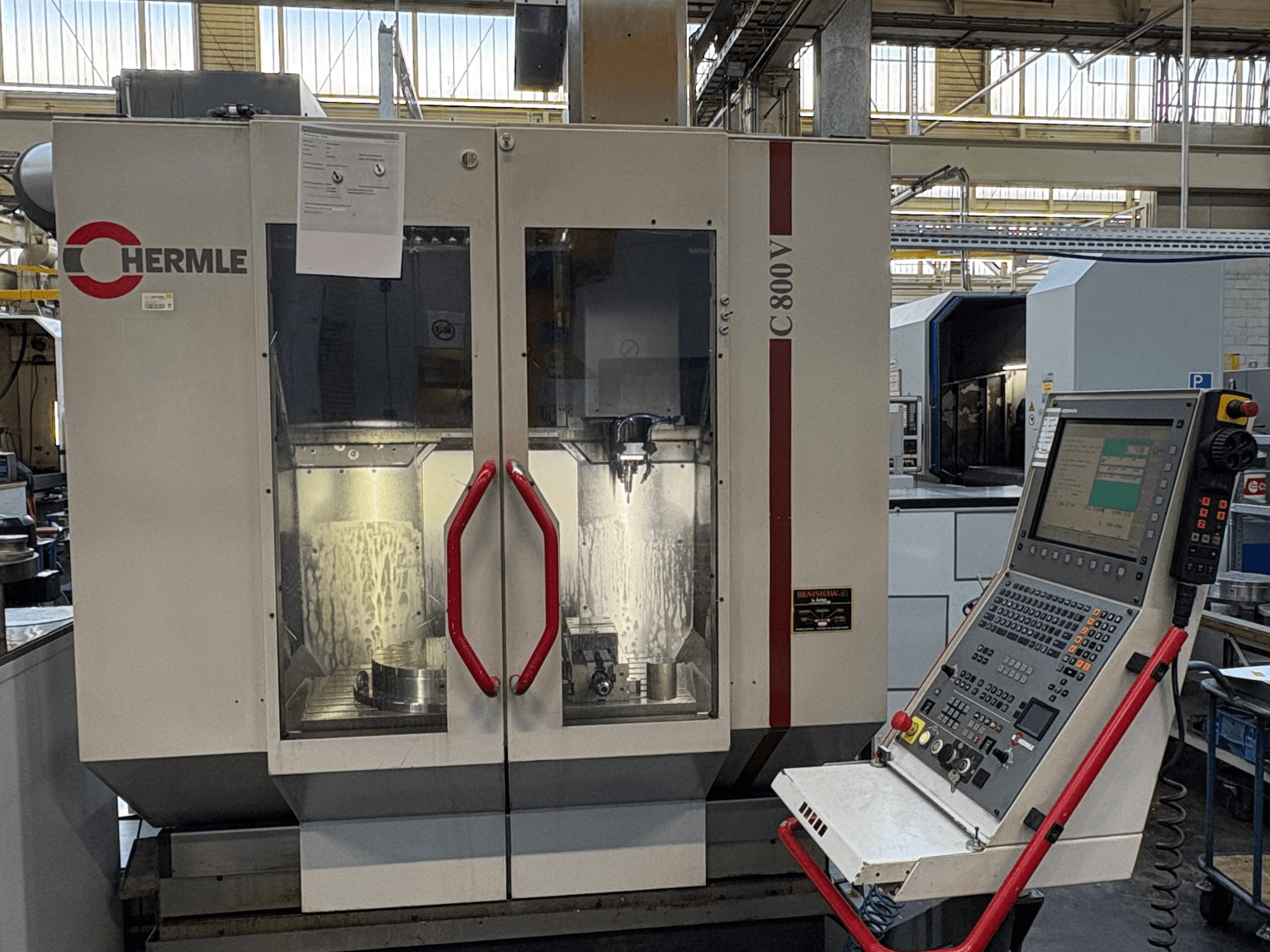 Вертикальний обробний центр HERMLE C 800 V, вид спереду, з дверцятами з червоними ручками та панеллю управління праворуч.