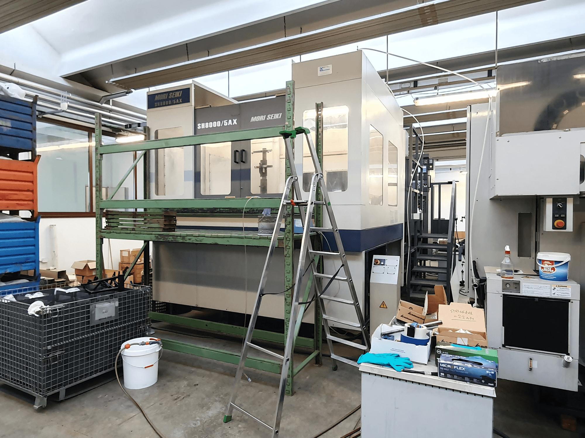 Верстат з ЧПК Mori Seiki SH-8000/5AX у майстерні, вид спереду, з інструментами та ящиками для зберігання поруч.