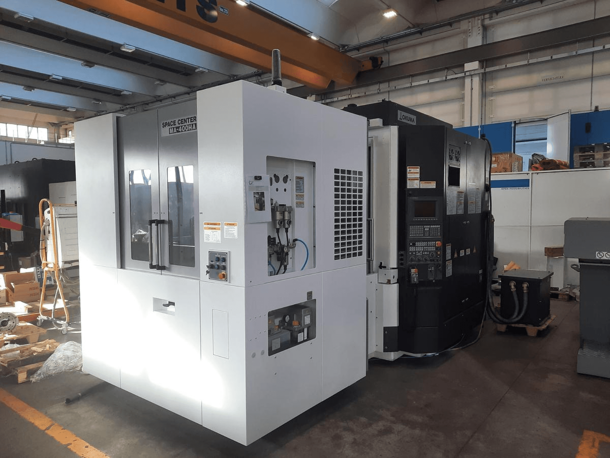 Вид спереду на верстати з ЧПК SPACE CENTER IM-400HAA та OKUMA, з різними елементами керування та етикетками виробника.