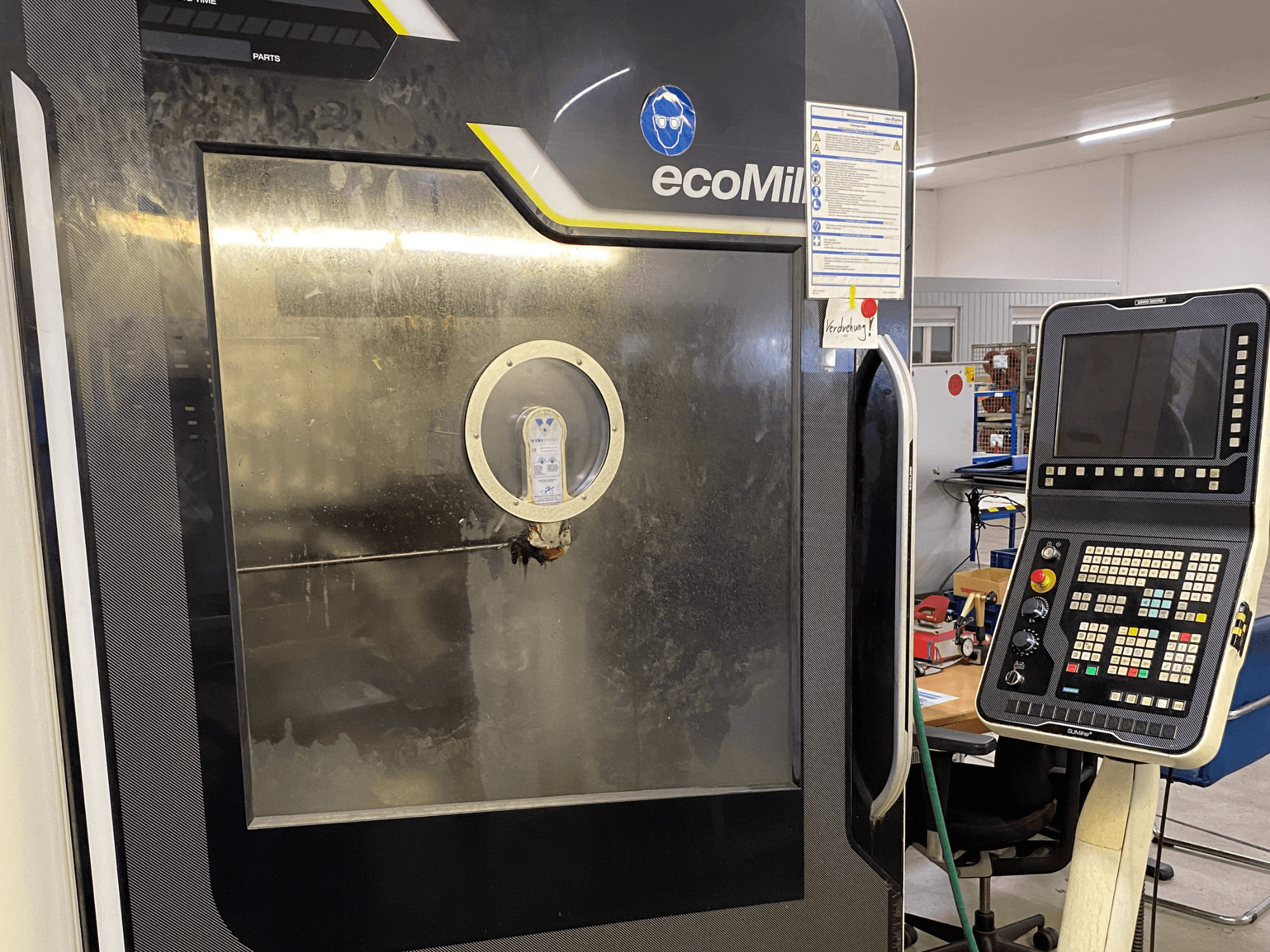 Фрезерний верстат DMG MU 70 ECO у фронтальному ракурсі: праворуч розташована панель керування, а скляна панель дозволяє побачити внутрішні компоненти.