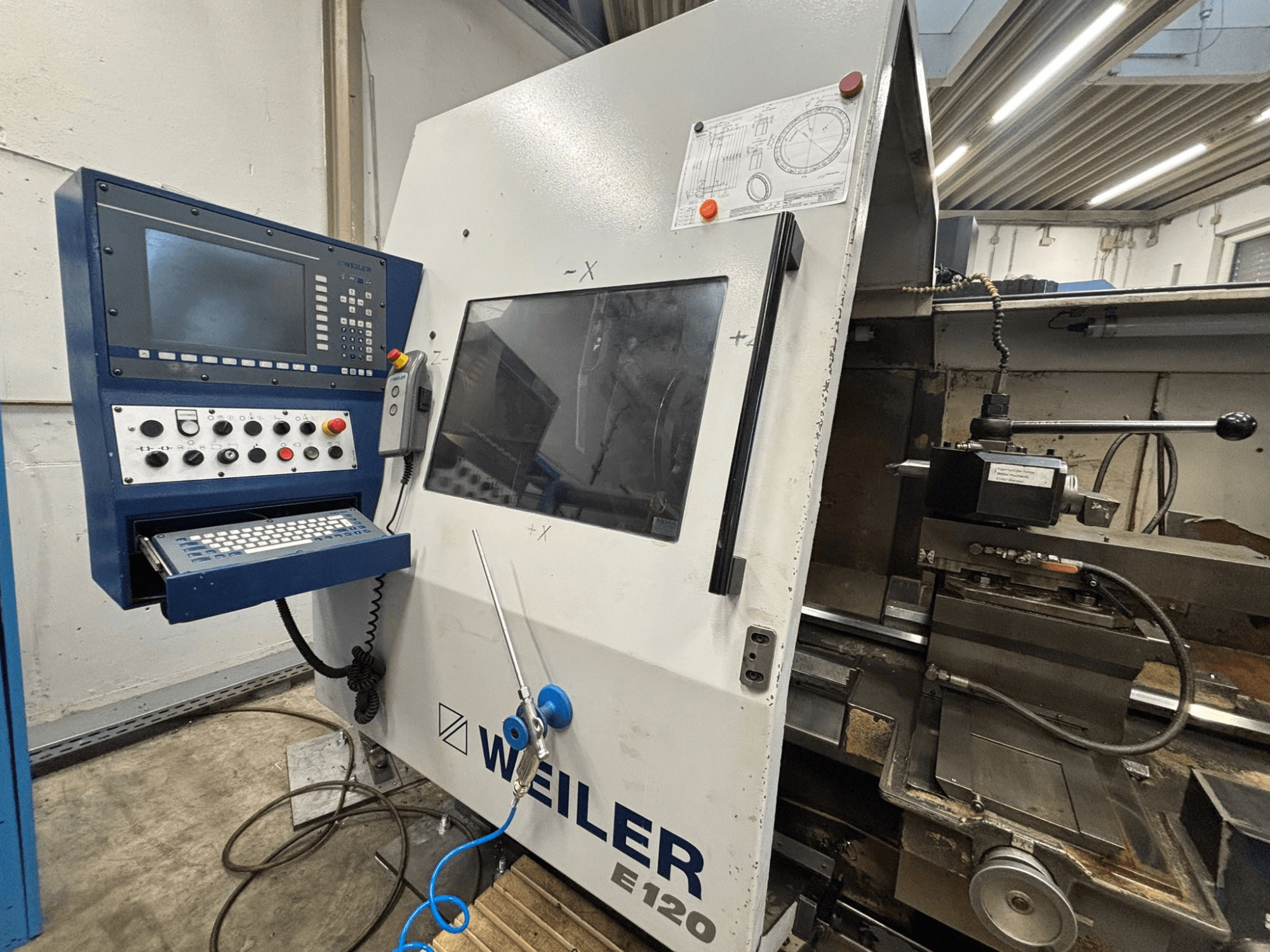 Панель керування та інтерфейс верстата з ЧПК Weiler E-120, вид спереду з видимими кнопками, екраном дисплея та робочими компонентами.