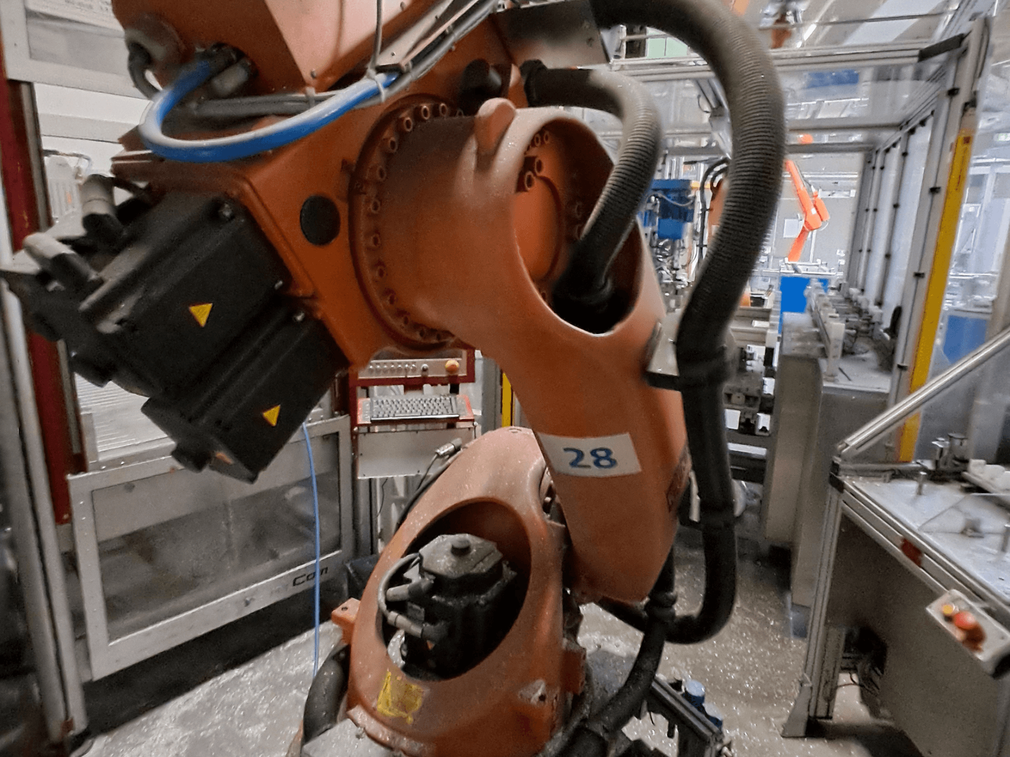 Збільшений план маніпулятора робота KUKA KR30-3: корпус помаранчевого кольору з маркуванням «28», на якому з боку видно двигуни та електропроводку.