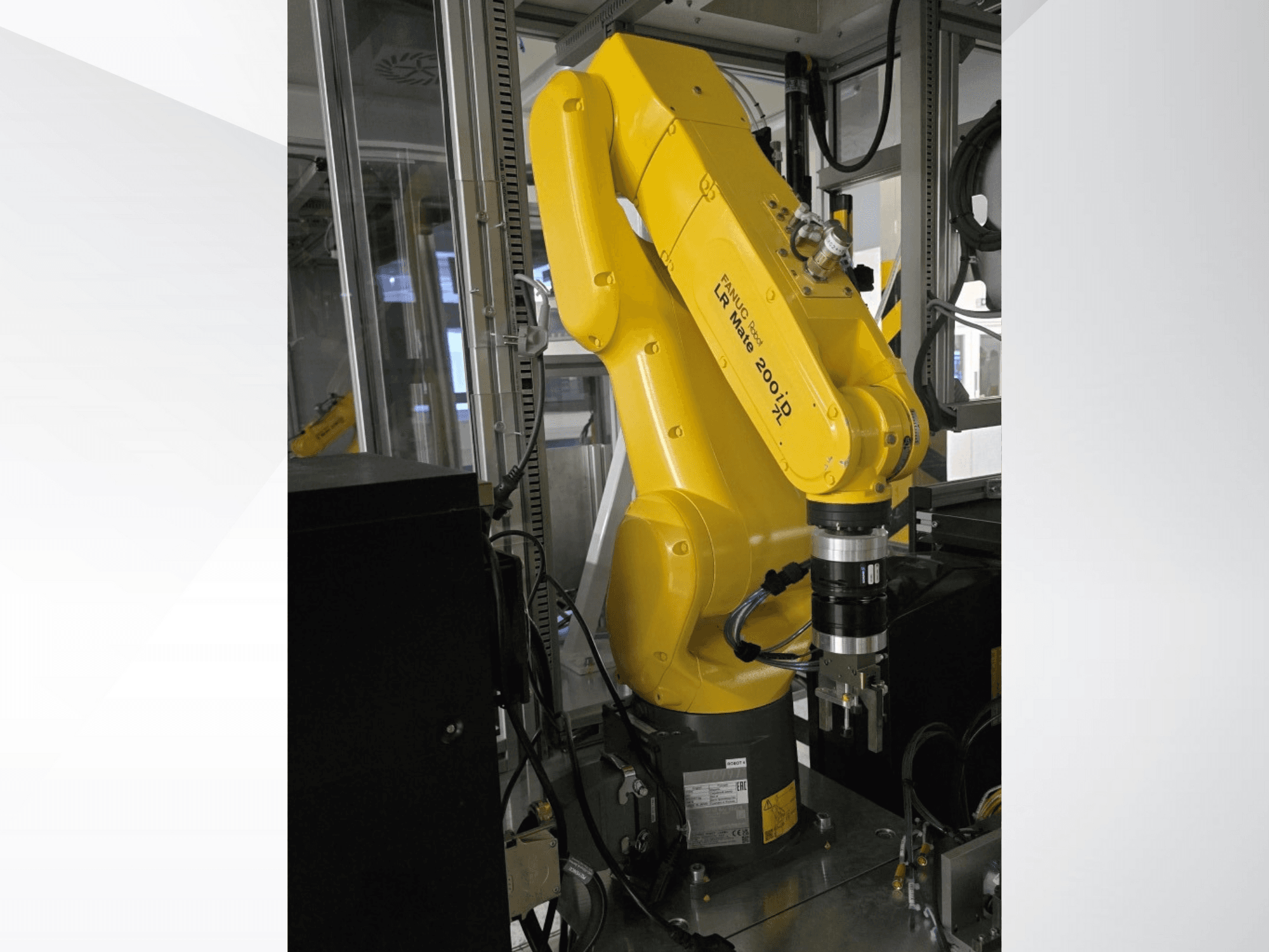 Жовтий роботизований маніпулятор Fanuc LR Mate 200iD показаний збоку, із захопленням і різними кабелями, прикріпленими до нього.