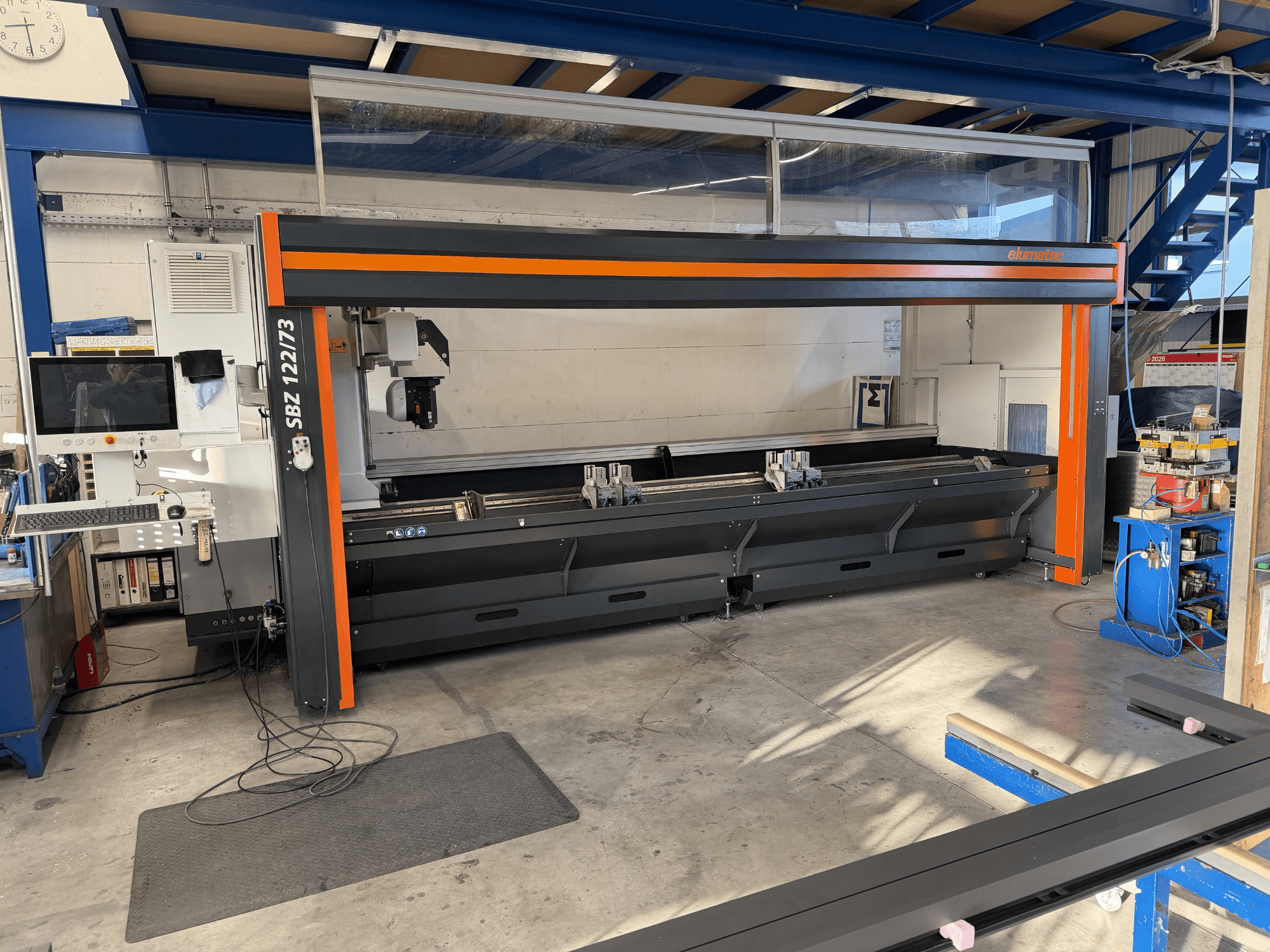 Верстат Elumatec SBZ 122/73 спереду, на якому показано панель керування, зону різання та планування робочого простору.