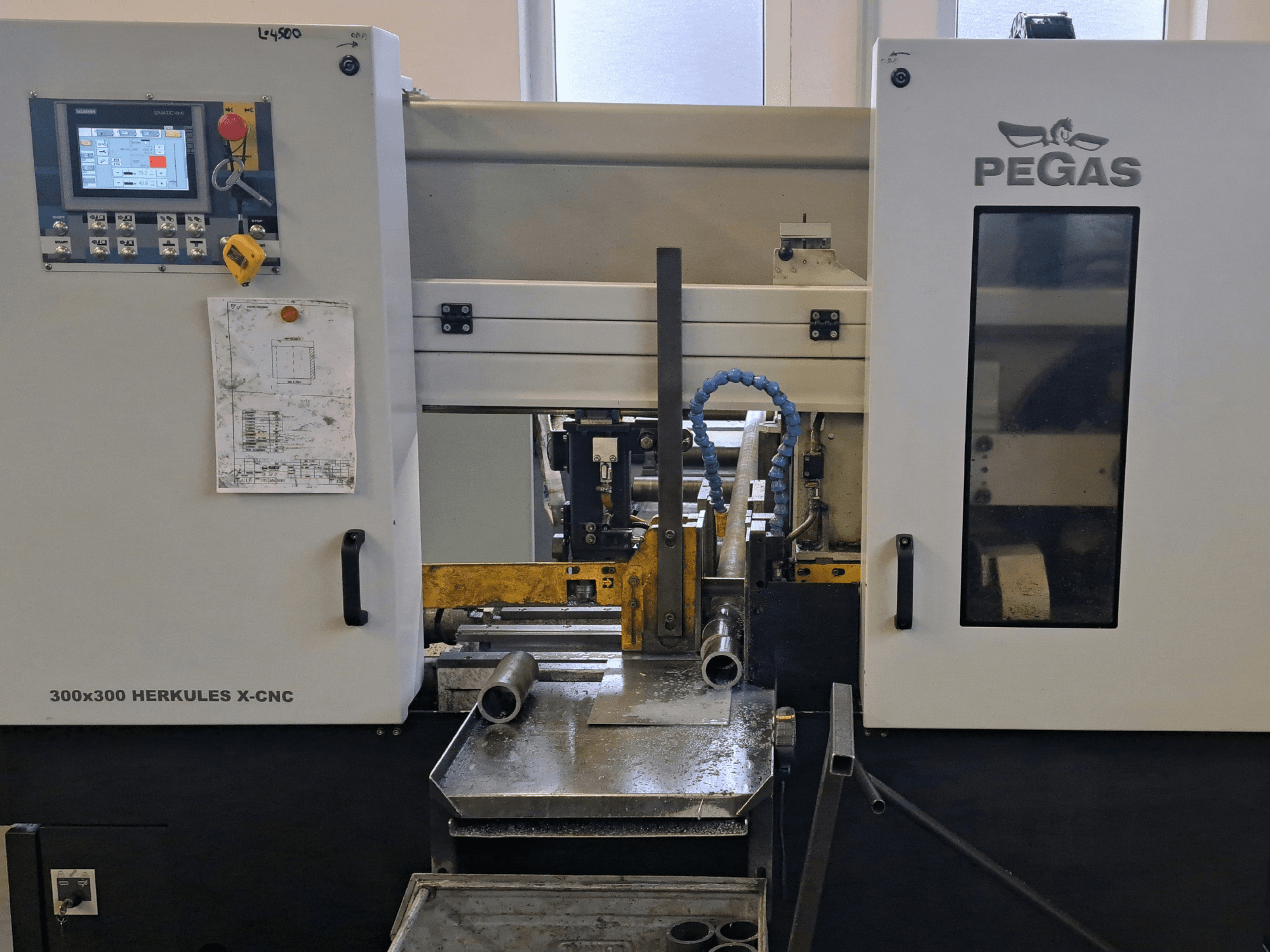 Верстат для обробки листового металу Pegas HERKULES X-CNC 300x300, вид спереду, на якому видно панель управління та робочу зону з металевими заготовками.