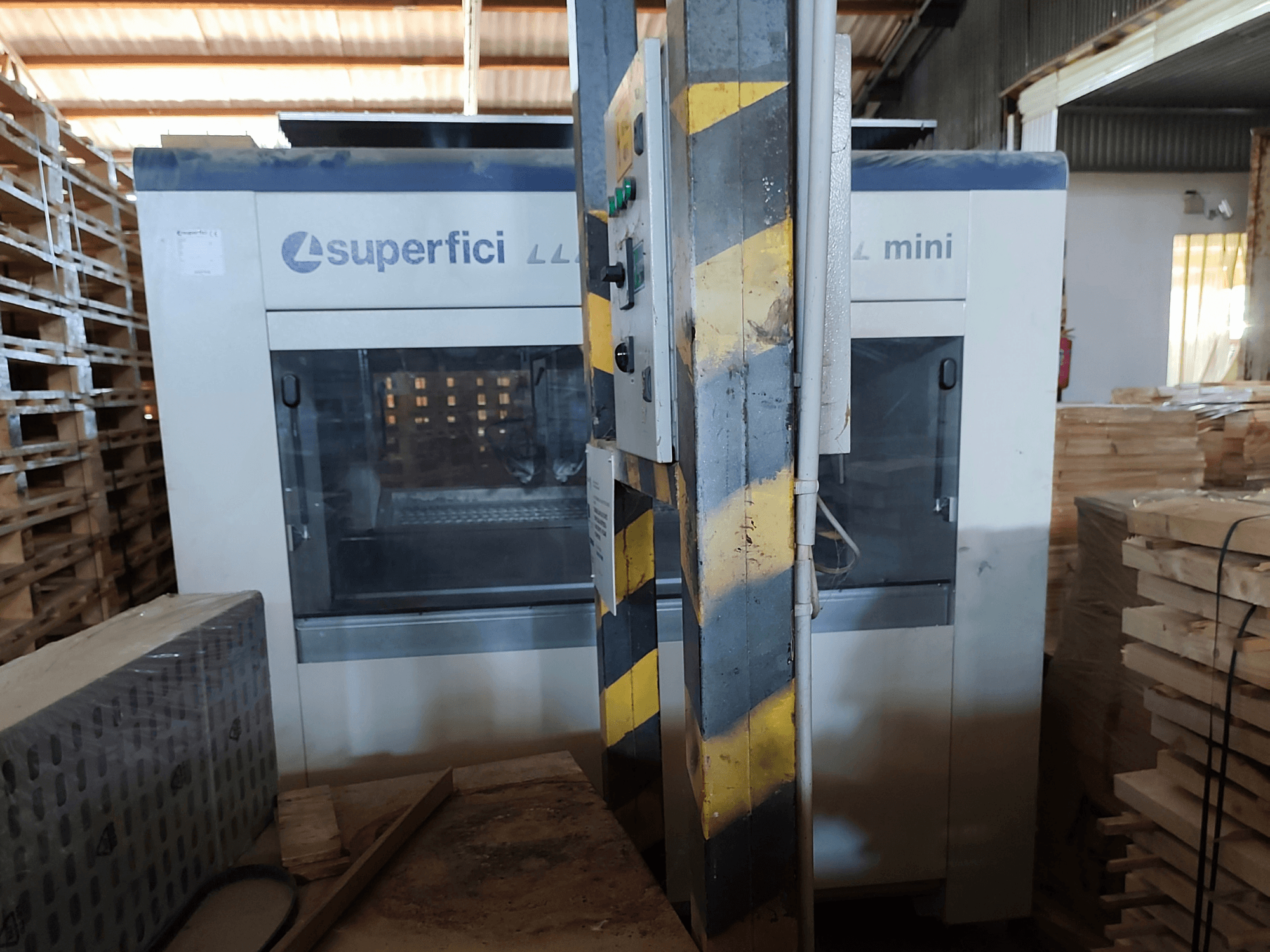 Деревообробна машина SCM Superfici Mini у фронтальному ракурсі: на фото видно панель управління та дерев’яні піддони навколо неї.