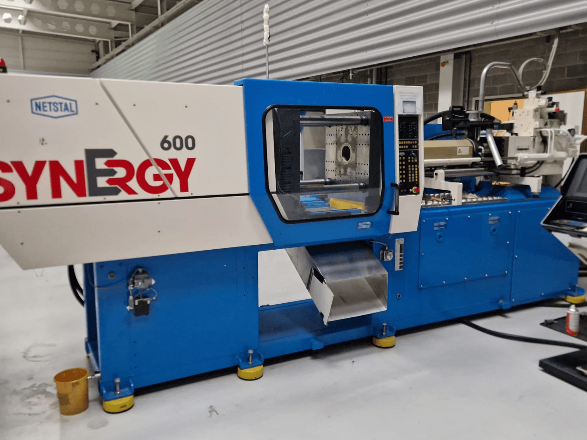 Гідравлічна машина для лиття під тиском Netstal Synergy 600-230, вид збоку з панеллю керування та зоною впорскування.