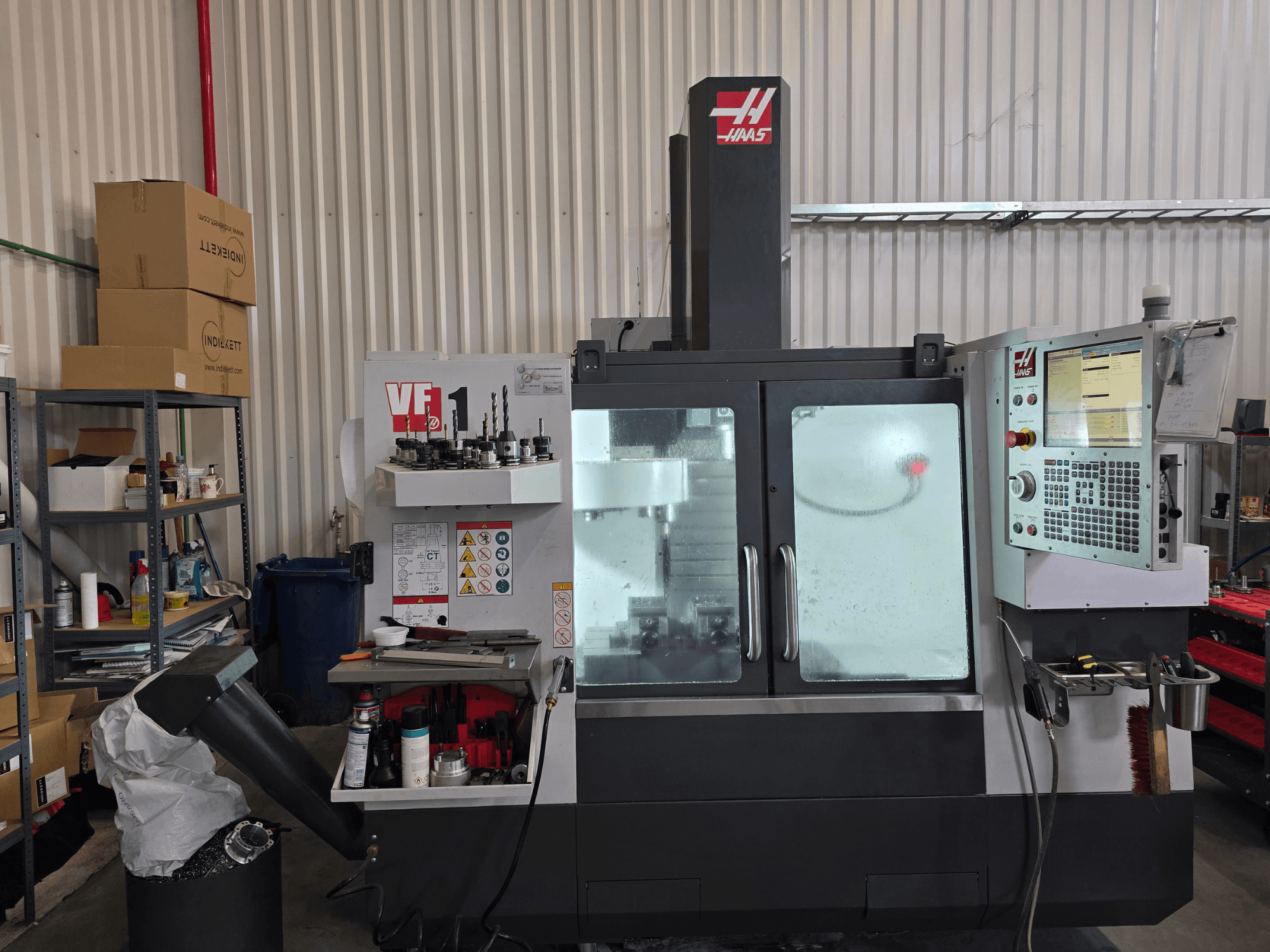 Вертикальний обробний центр HAAS VF 1 в майстерні, вид спереду, що демонструє панель керування та зону фрезерування з інструментами.