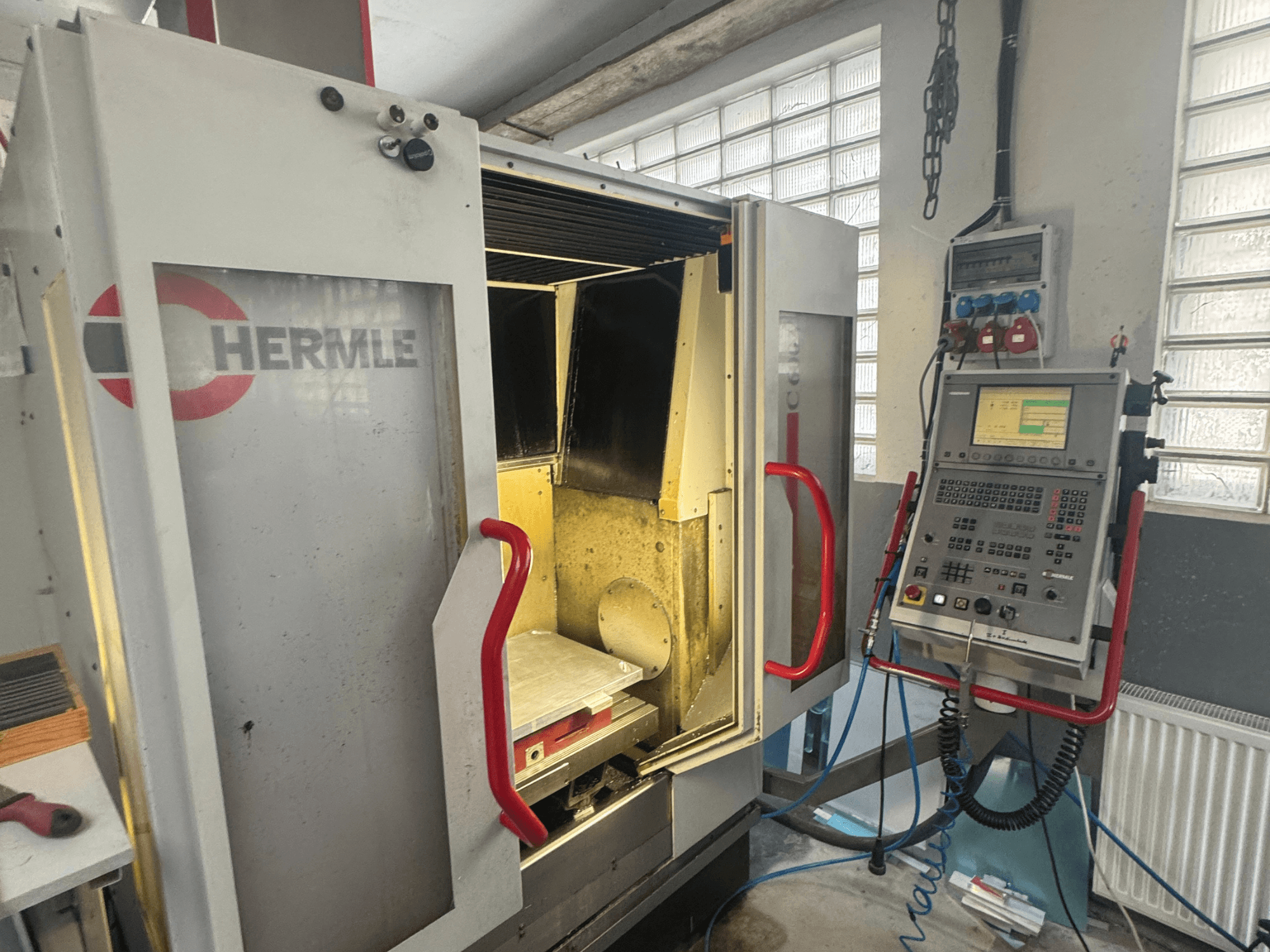 Вертикальний обробний центр HERMLE C600V, вид спереду з відкритими дверима, панеллю керування та внутрішньою робочою зоною.