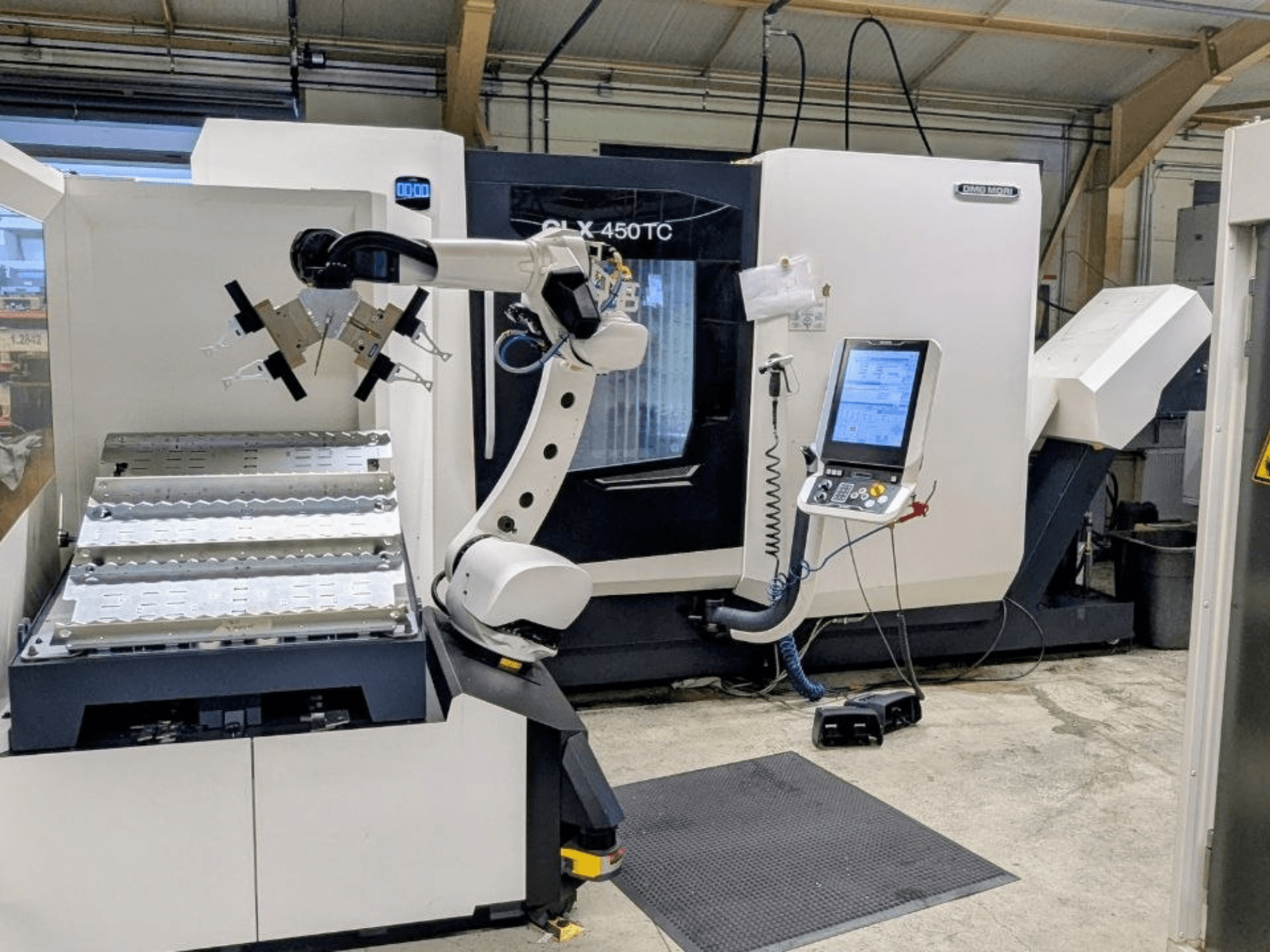 DMG MORI CLX 450 TC з Robo2go, вид спереду, на якому видно робочий маніпулятор та панель керування поруч із верстатом.