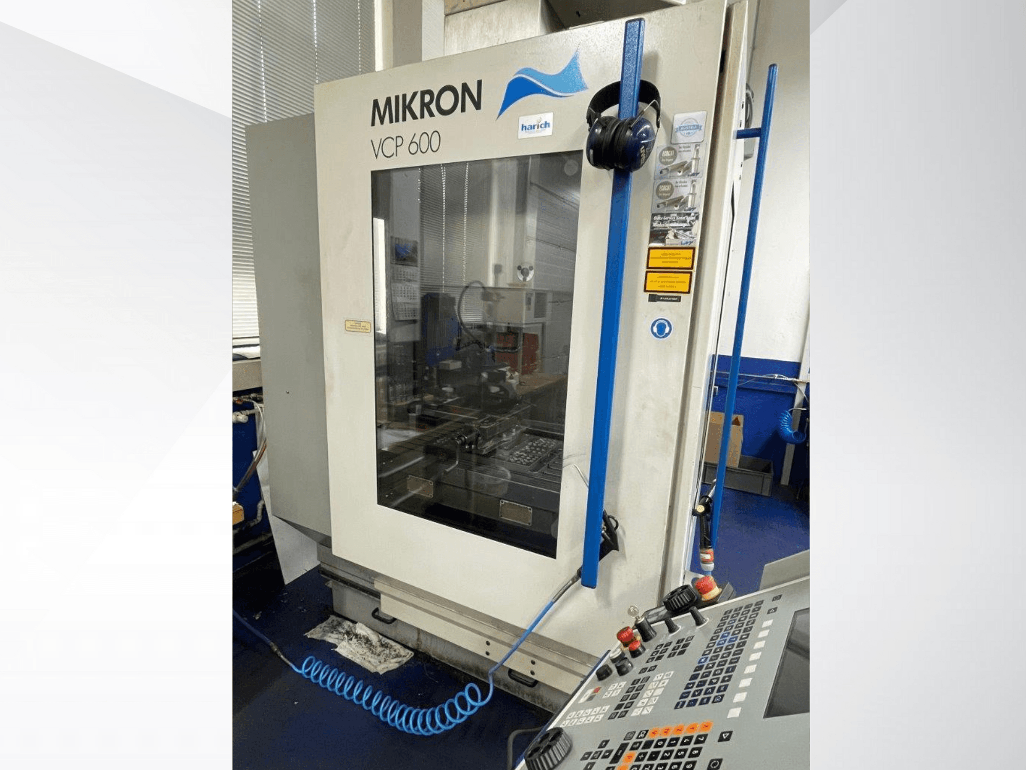 Верстат з ЧПК Mikron VCP 600, вид спереду, з панеллю керування з кнопками та видимою зоною обробки за склом.