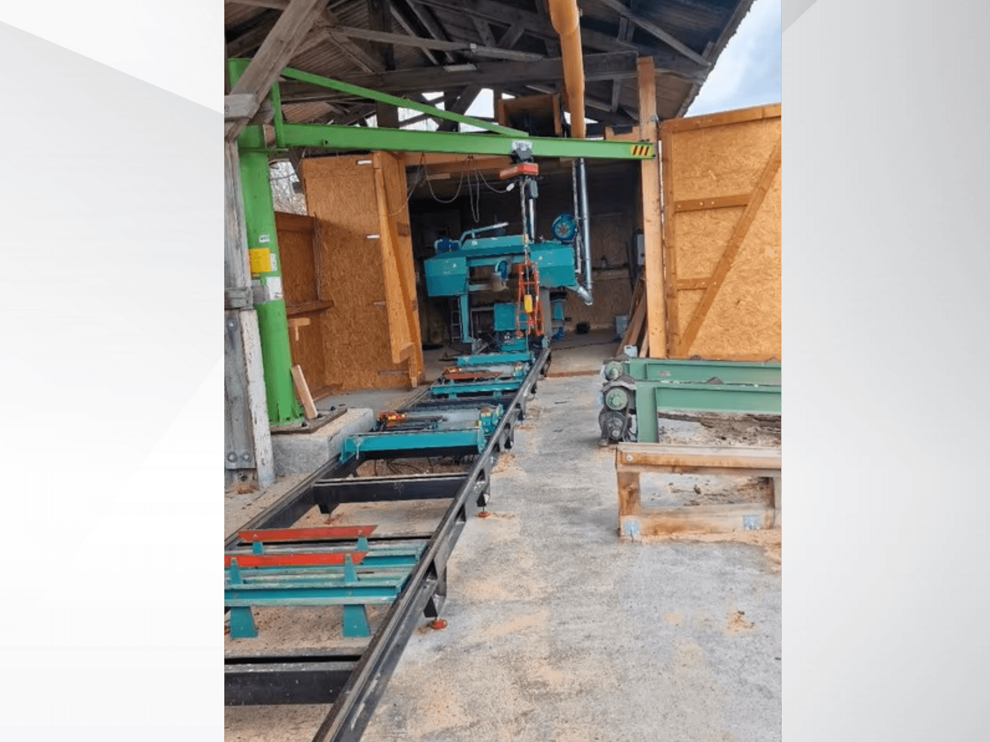 Горизонтальний стрічкопильний верстат у майстерні, вид спереду. Устаткування включає в себе трек і додаткові зелені аксесуари.