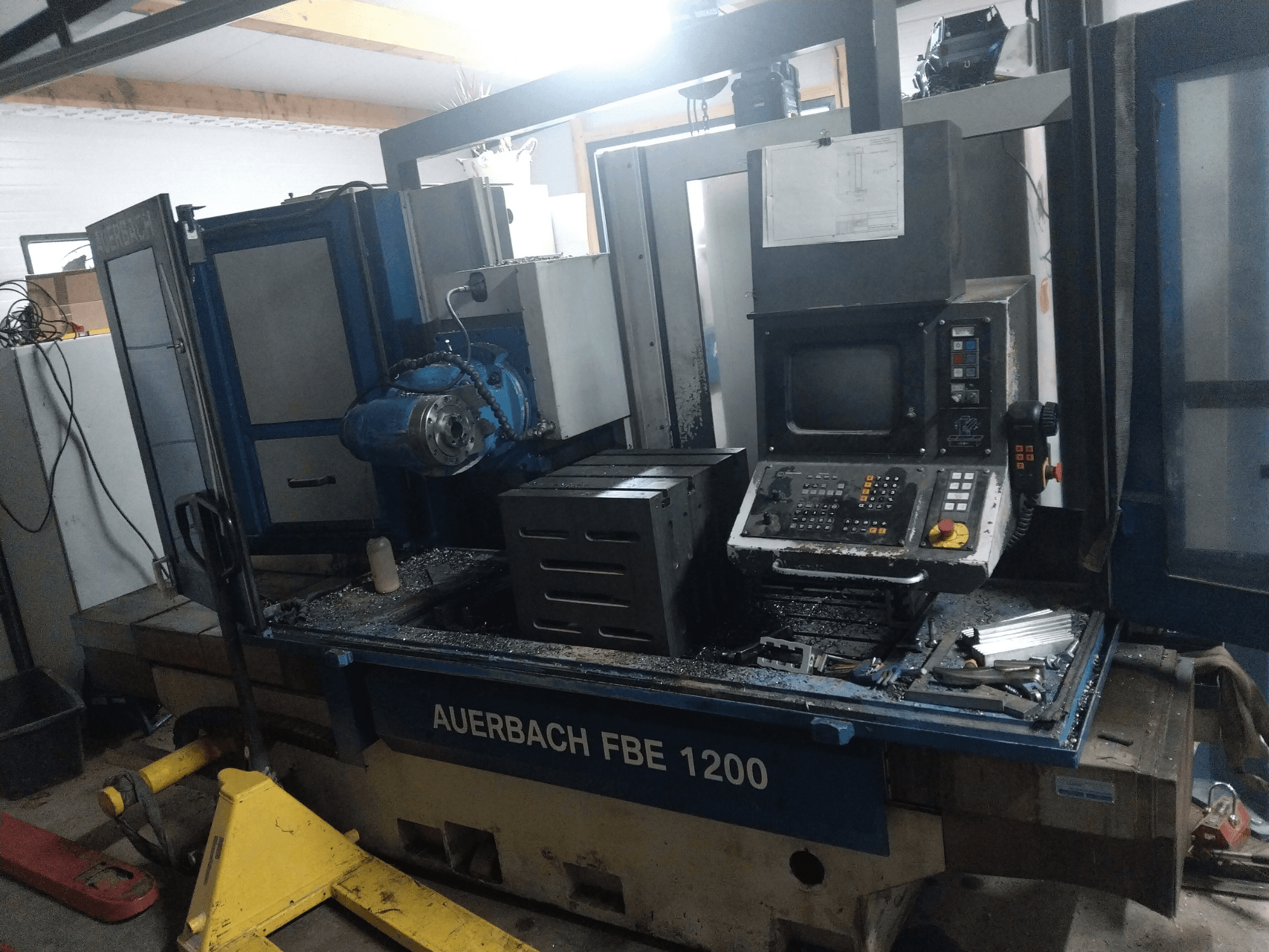 Свердлильний верстат Auerbach FBE 1200, вид спереду, з панеллю керування, двигуном і металевою стружкою на робочій поверхні.