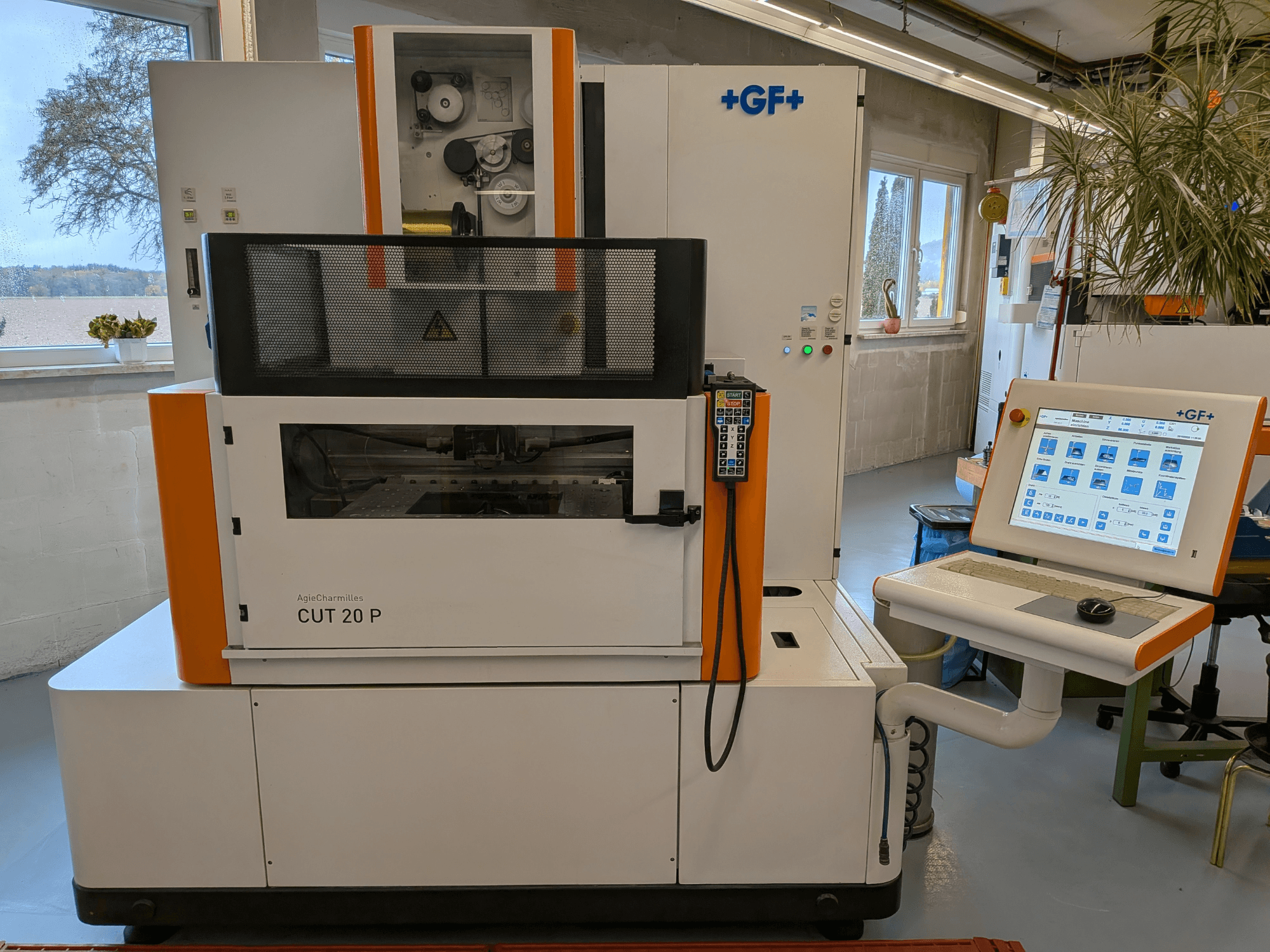 Електроерозійна машина для дротової обробки AgieCharmilles Cut-20 P у фронтальному ракурсі з панеллю керування та дисплеєм, встановлена у добре освітленому цеху.