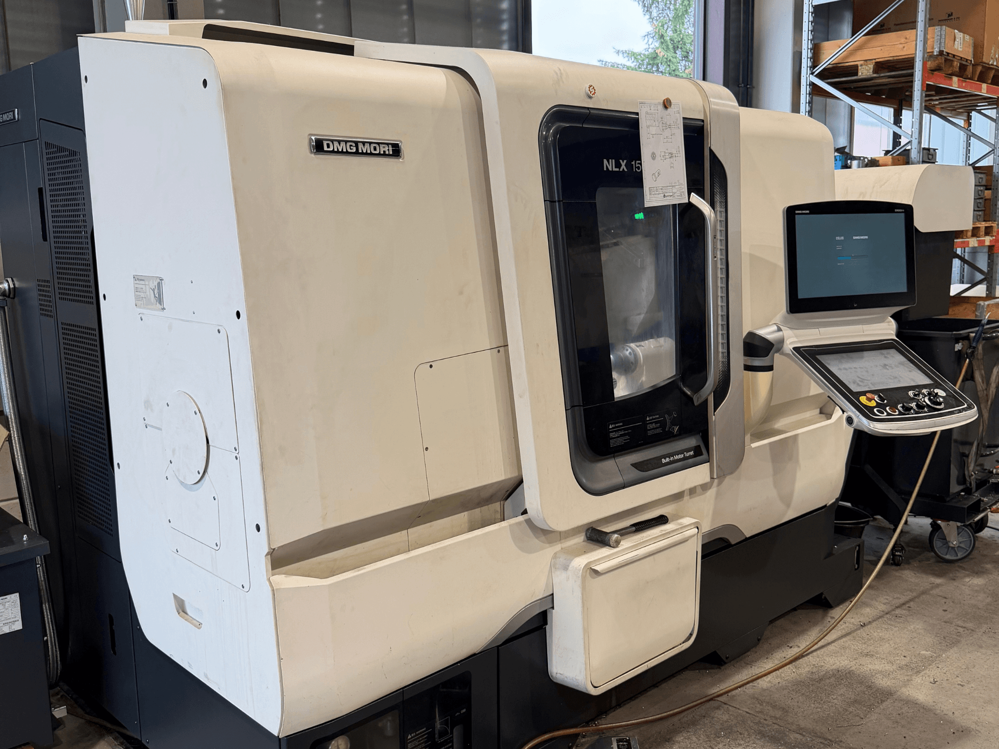 Вигляд спереду горизонтального токарного верстата DMG MORI NLX1500MC/500, на якому через прозору кришку видно панель управління та зону шпинделя.