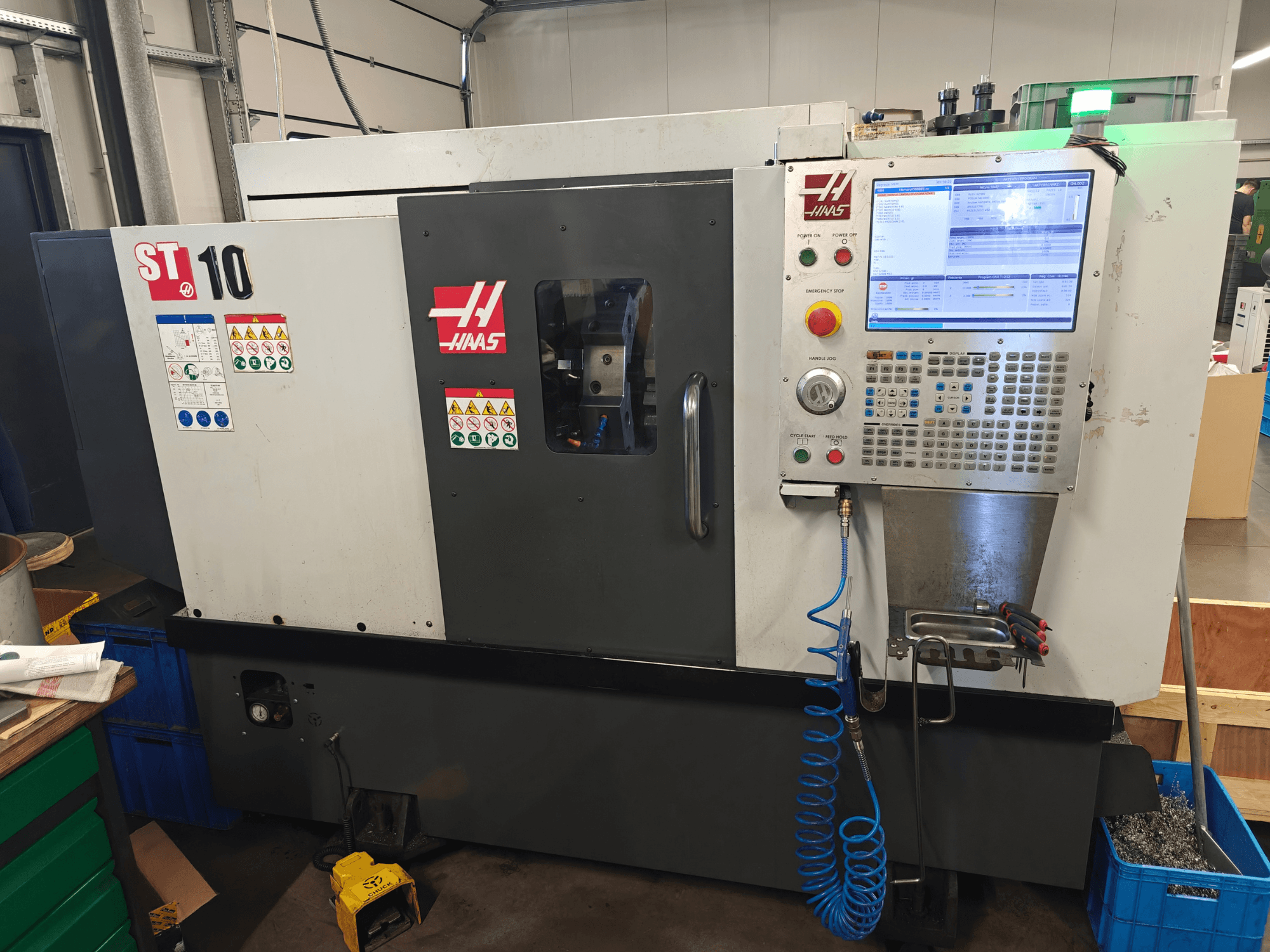 Горизонтальний токарний верстат Haas ST-10, вид спереду, на якому видно панель управління, попереджувальні наклейки та конструкцію верстата.