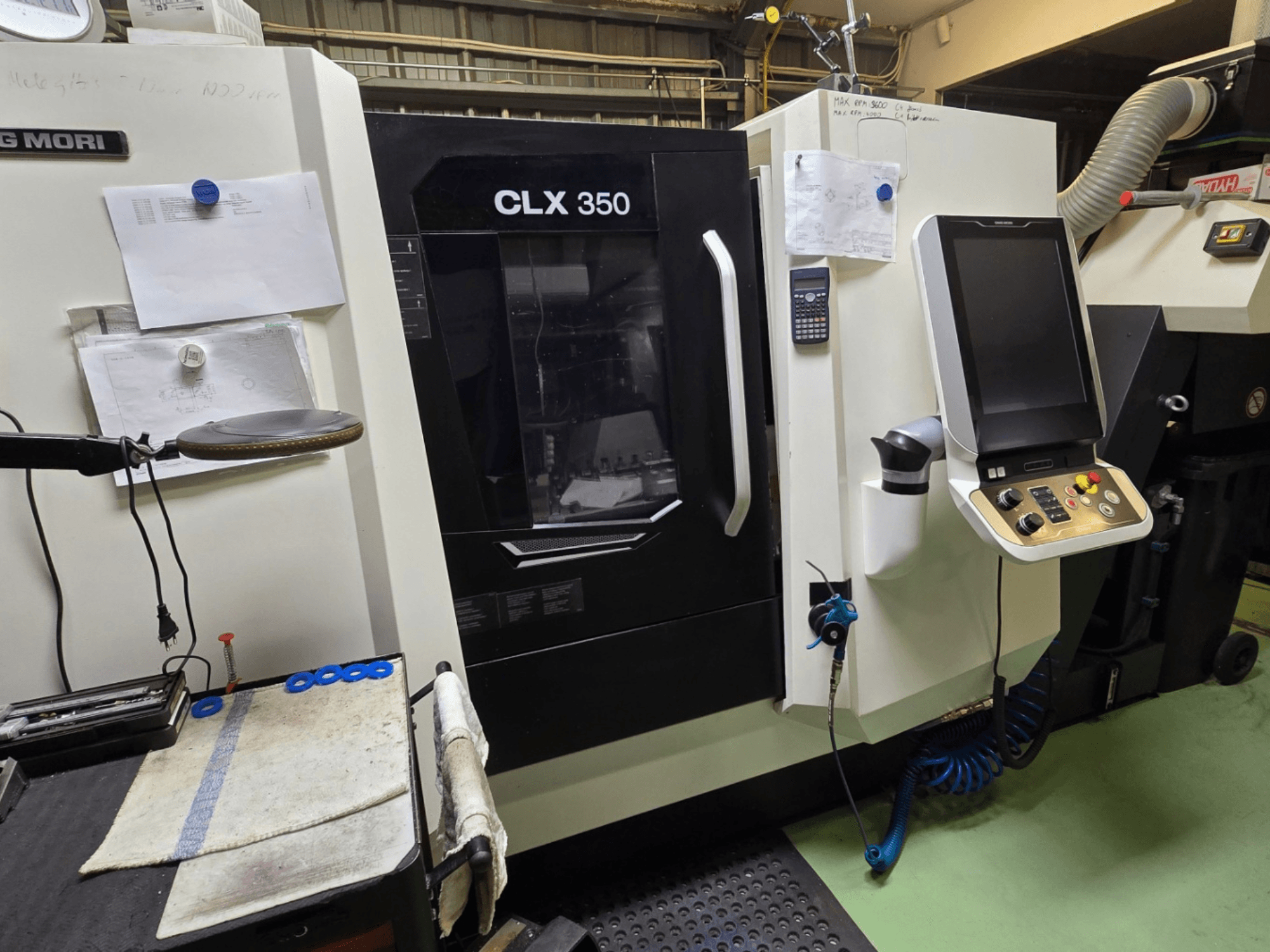 Токарний верстат з ЧПК DMG MORI CLX 350 в майстерні; вид спереду з панеллю керування, інструментами та робочим простором.