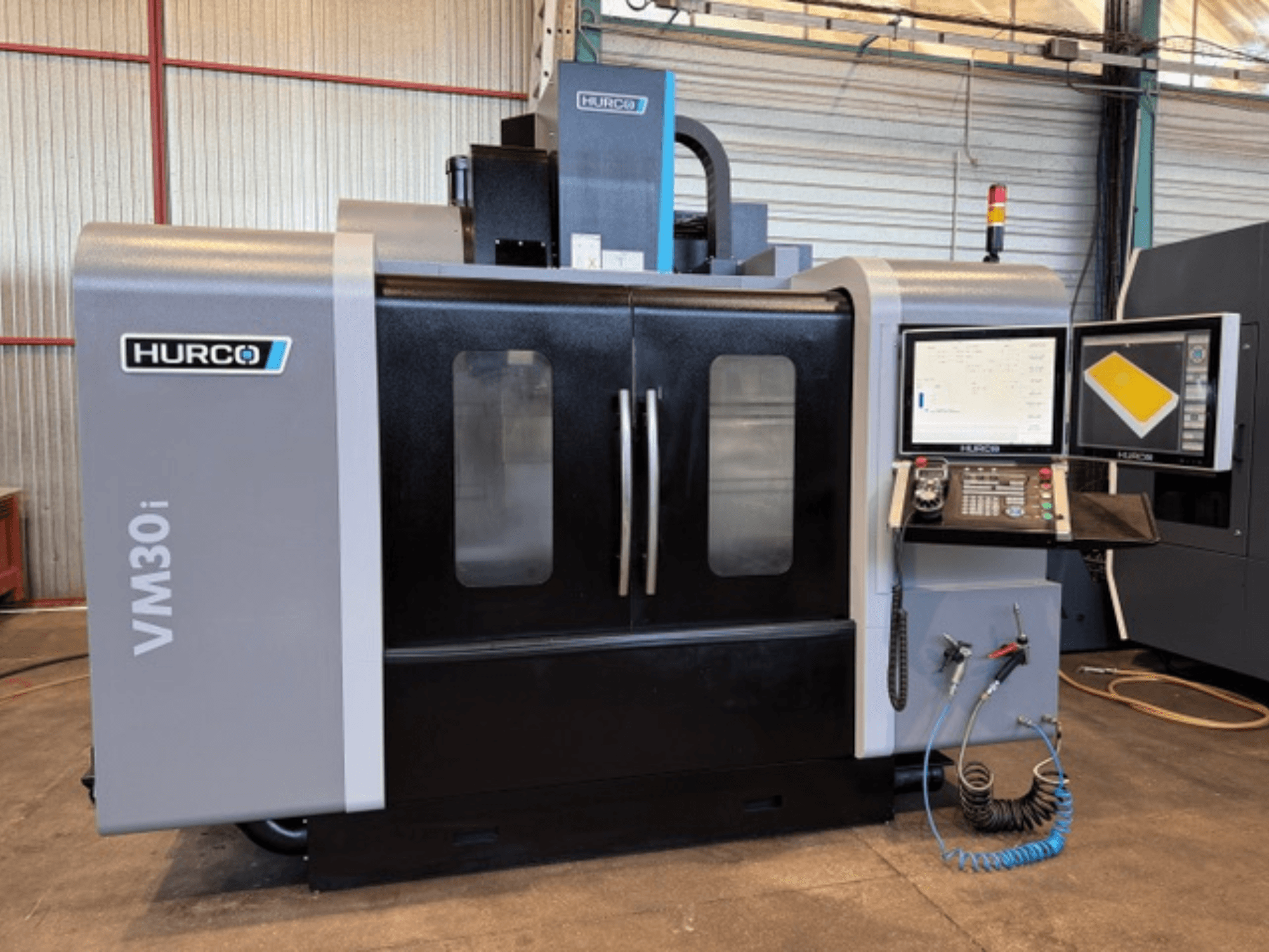 Вертикальний обробний центр Hurco VM30i, вид спереду, що демонструє панель керування, екрани дисплеїв і двері верстата.