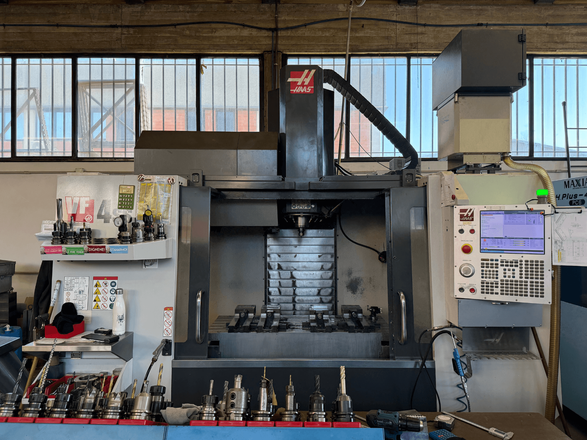Вертикальний обробний центр HAAS VF-4SS, вид спереду, на якому видно панель управління, тримачі інструментів та зону шпинделя.