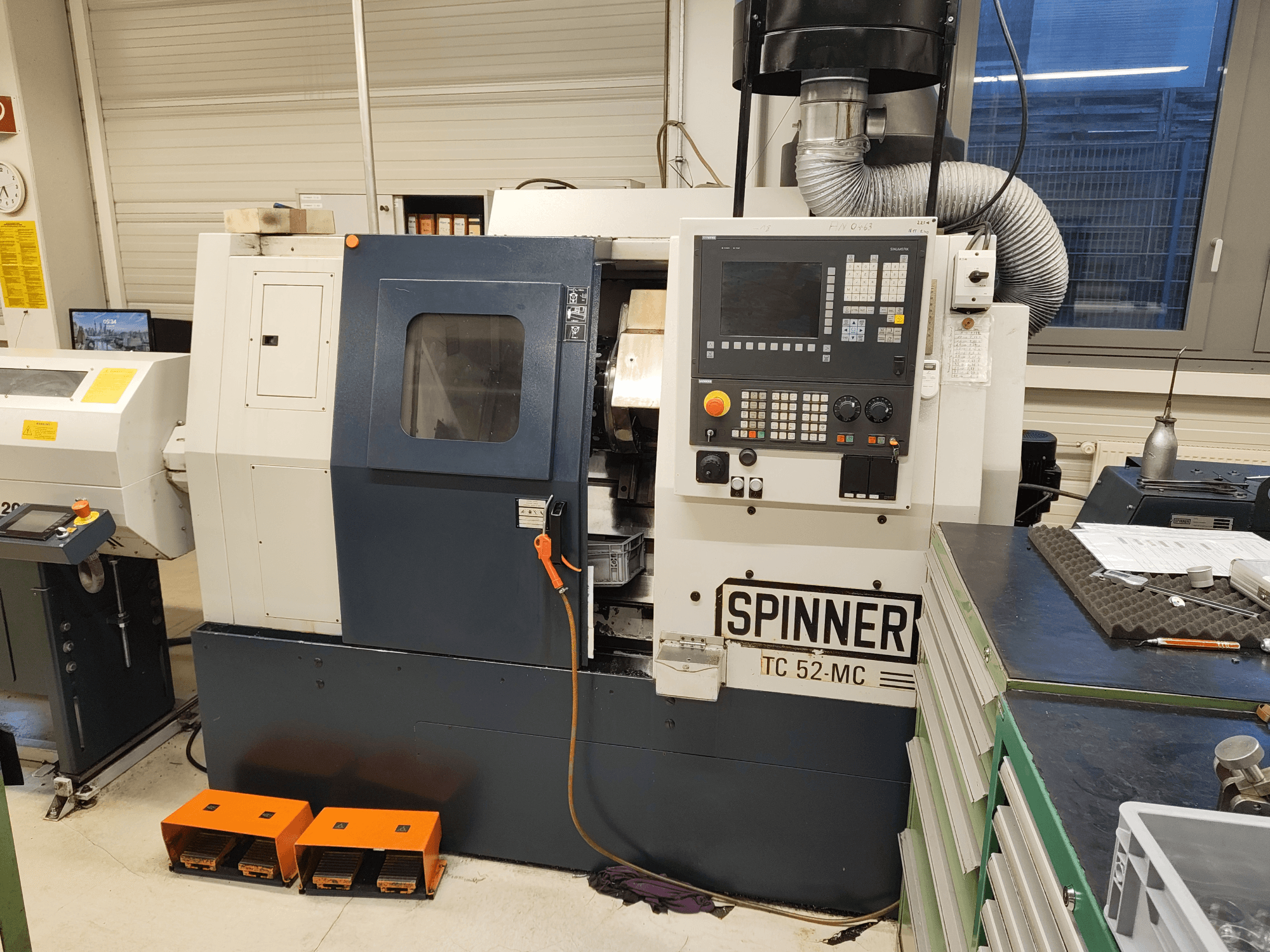 Горизонтальний токарний верстат SPINNER TC 52 MC у цеху, вид спереду, на якому видно панель управління, робочу зону та засоби безпеки.
