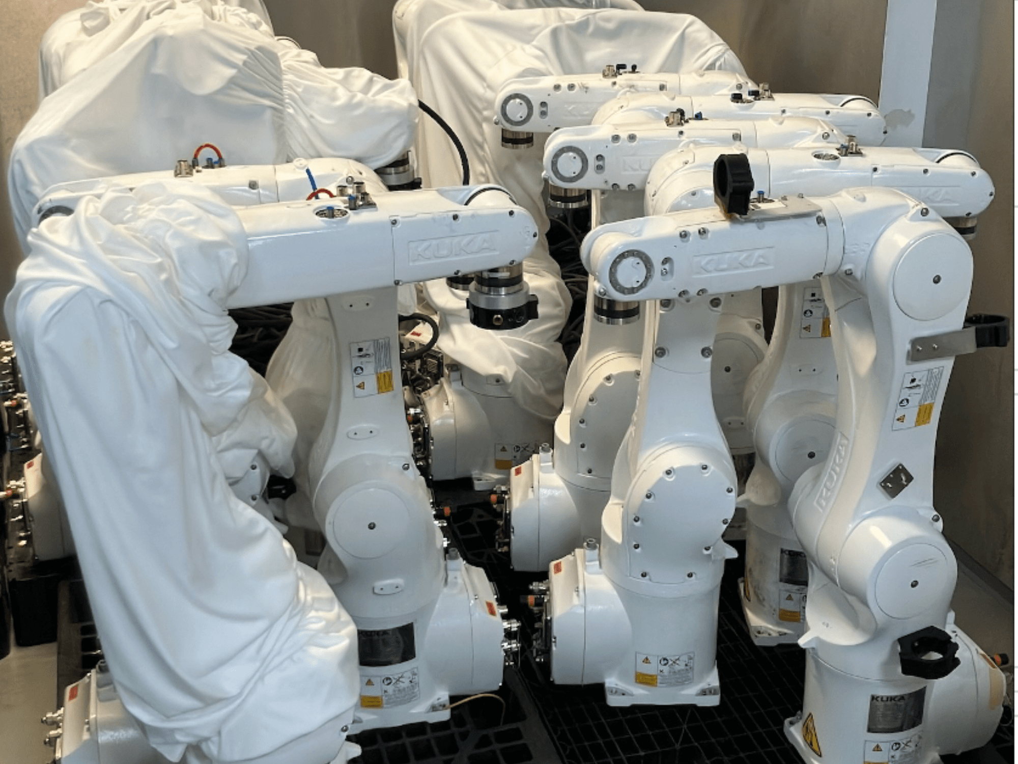Руки робота KUKA KR 10 R900-2, частково покриті тканиною, вид спереду, демонструючи їх гладкий білий дизайн і технічні деталі.