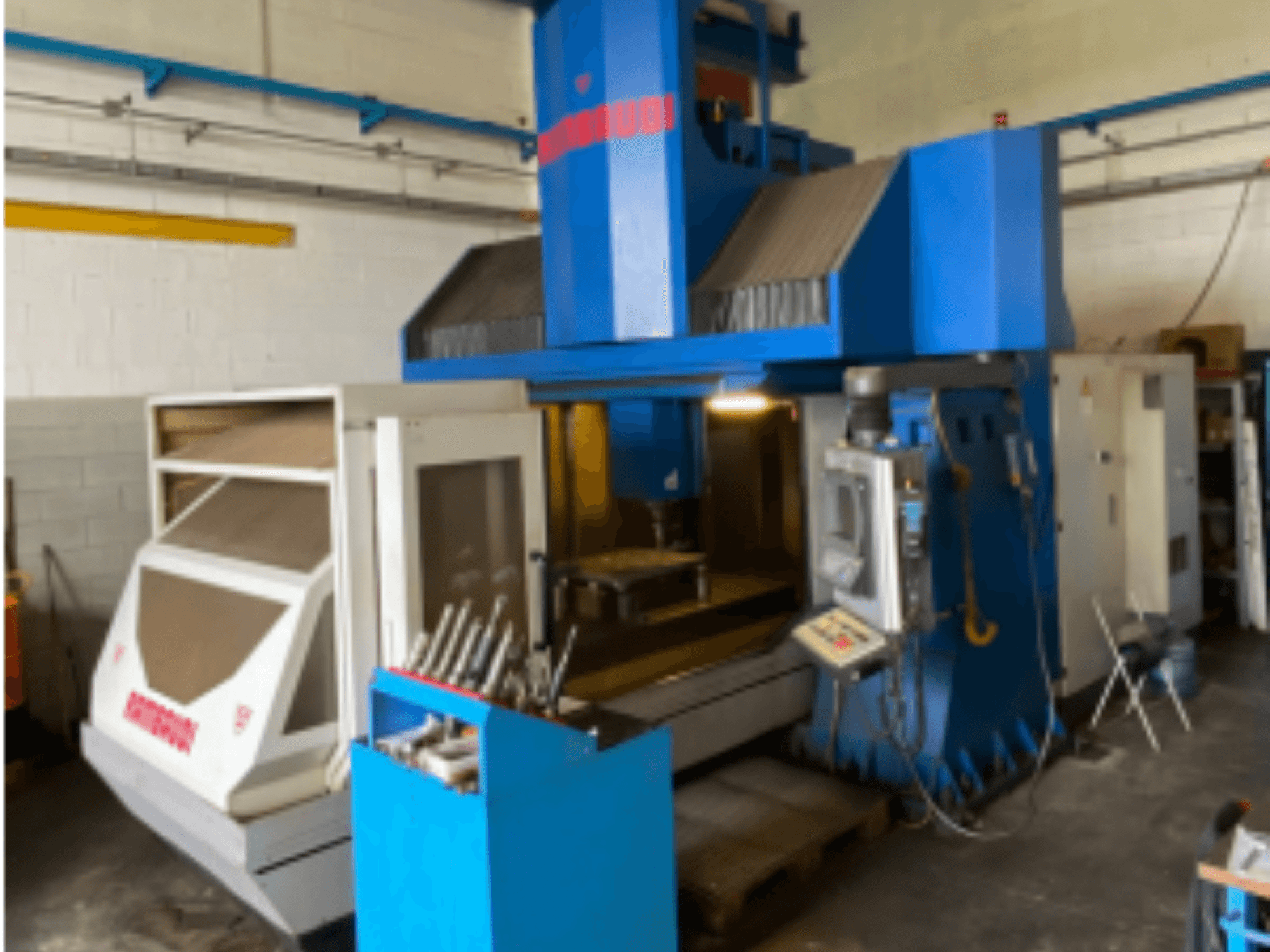 Вертикальний обробний центр Rambaudi RF103, вид спереду з елементами керування, місцем для зберігання інструменту та зоною обробки. Синьо-білий зовнішній вигляд.