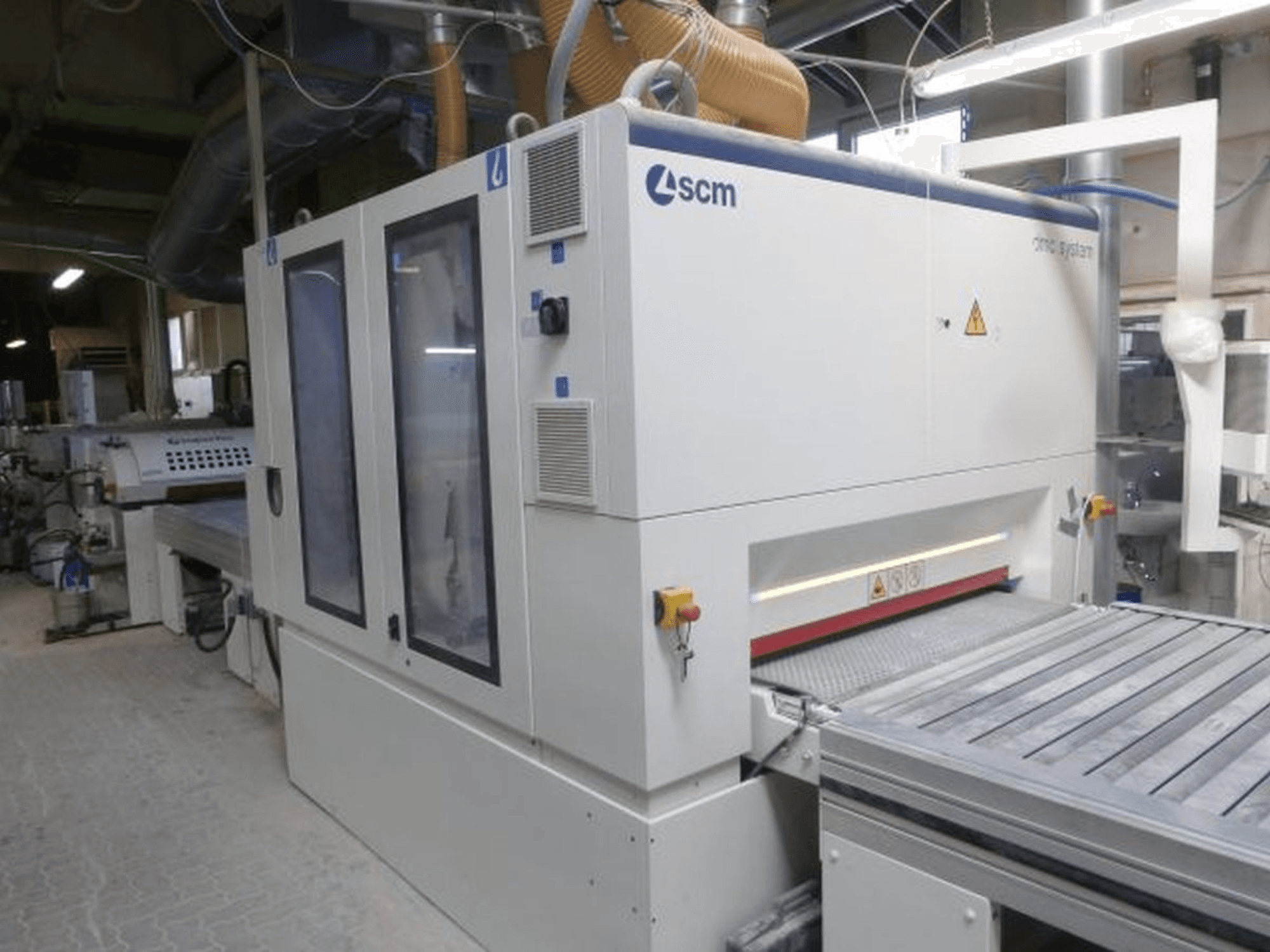 Лентошліфувальна машина SCM DMC SY TC 1350 у майстерні, вид збоку, на якому видно панель управління та шліфувальну поверхню з елементами безпеки.
