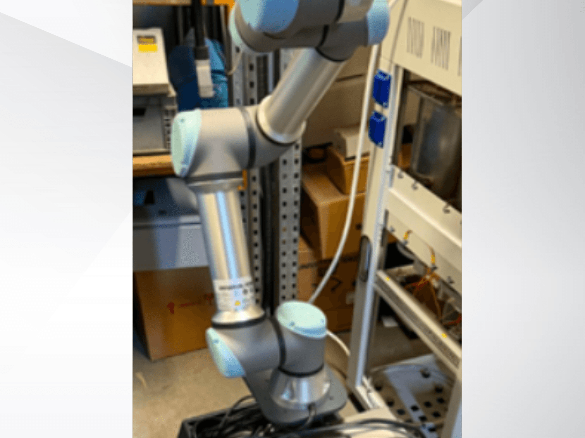 Роботизована рука Universal Robots UR5e, вид збоку, на якій видно шарнірні з'єднання, легку конструкцію та кабелі управління.