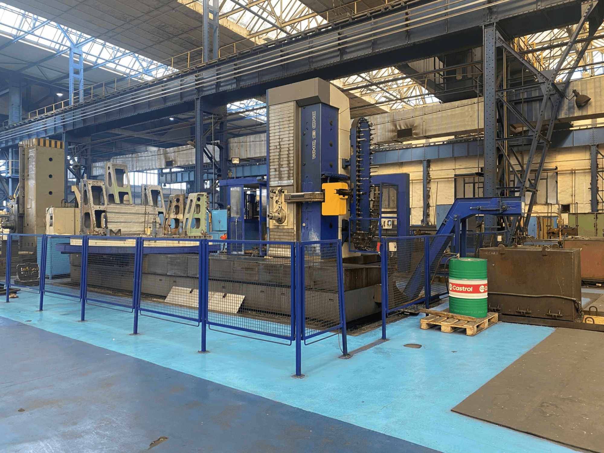 Розточувальний верстат з ЧПК TOS WHQ 13 в майстерні, вид спереду, видно синю раму і захисну огорожу навколо.