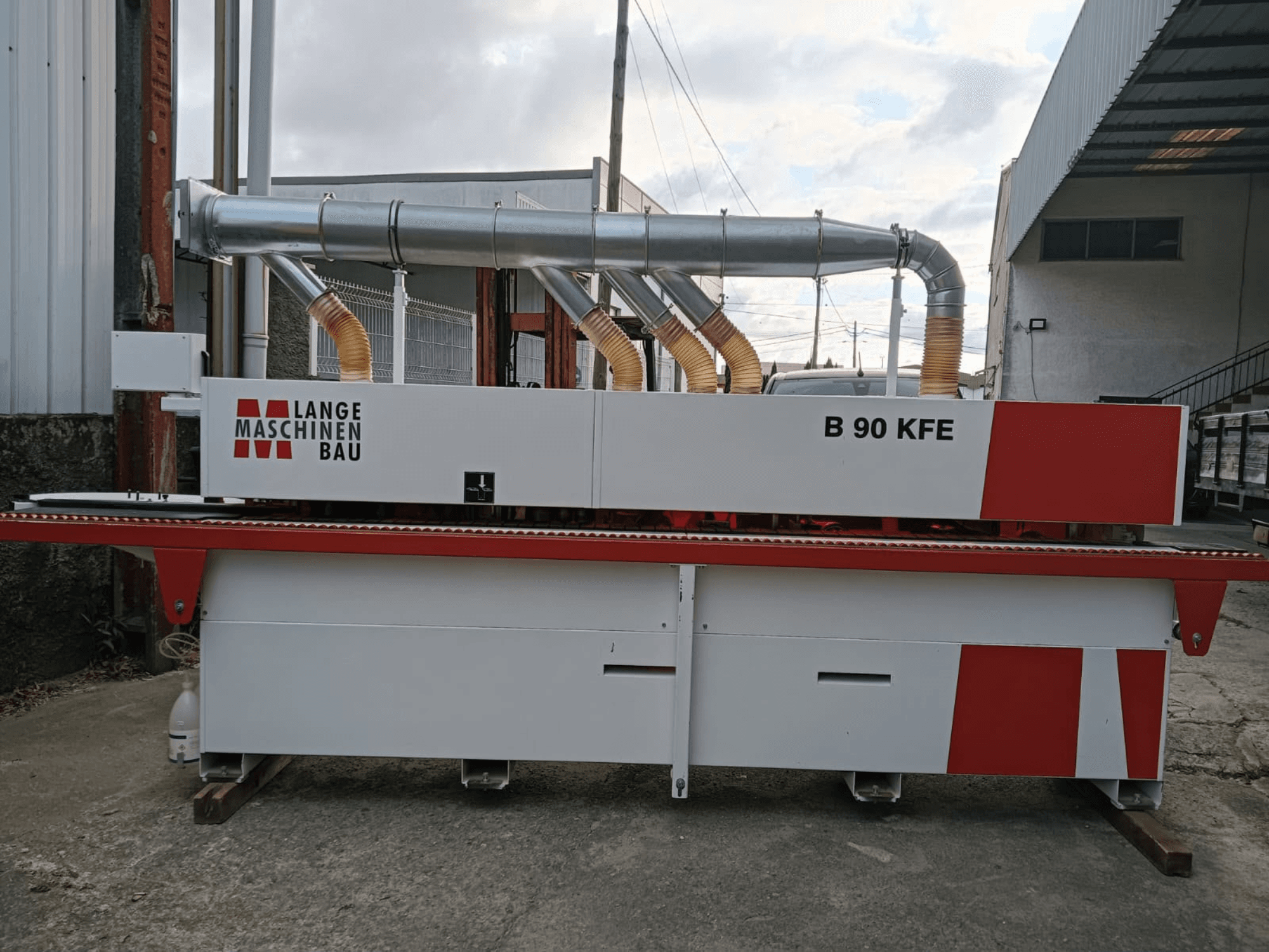 Кромкооблицювальна машина LANGE Maschinenbau B 90 KFE у боковому ракурсі з двома вихлопними трубами та червоними акцентами, встановлена в промисловому виробничому приміщенні.