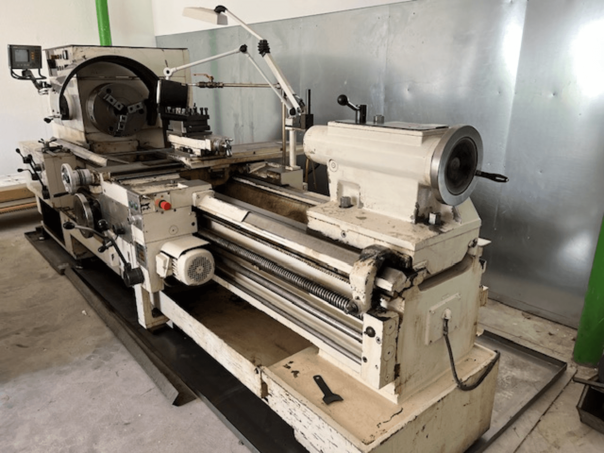 Старовинний токарний верстат з панеллю керування та інструментами, вид збоку, показує робочі елементи та обробку металу.