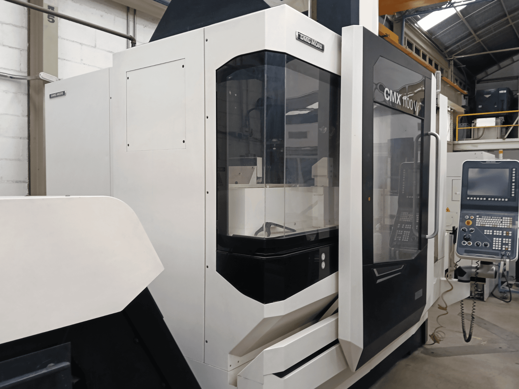 Вертикальний обробний центр DMG MORI CMX 1100 V, вид спереду, на якому видно панель керування та скляний кожух.