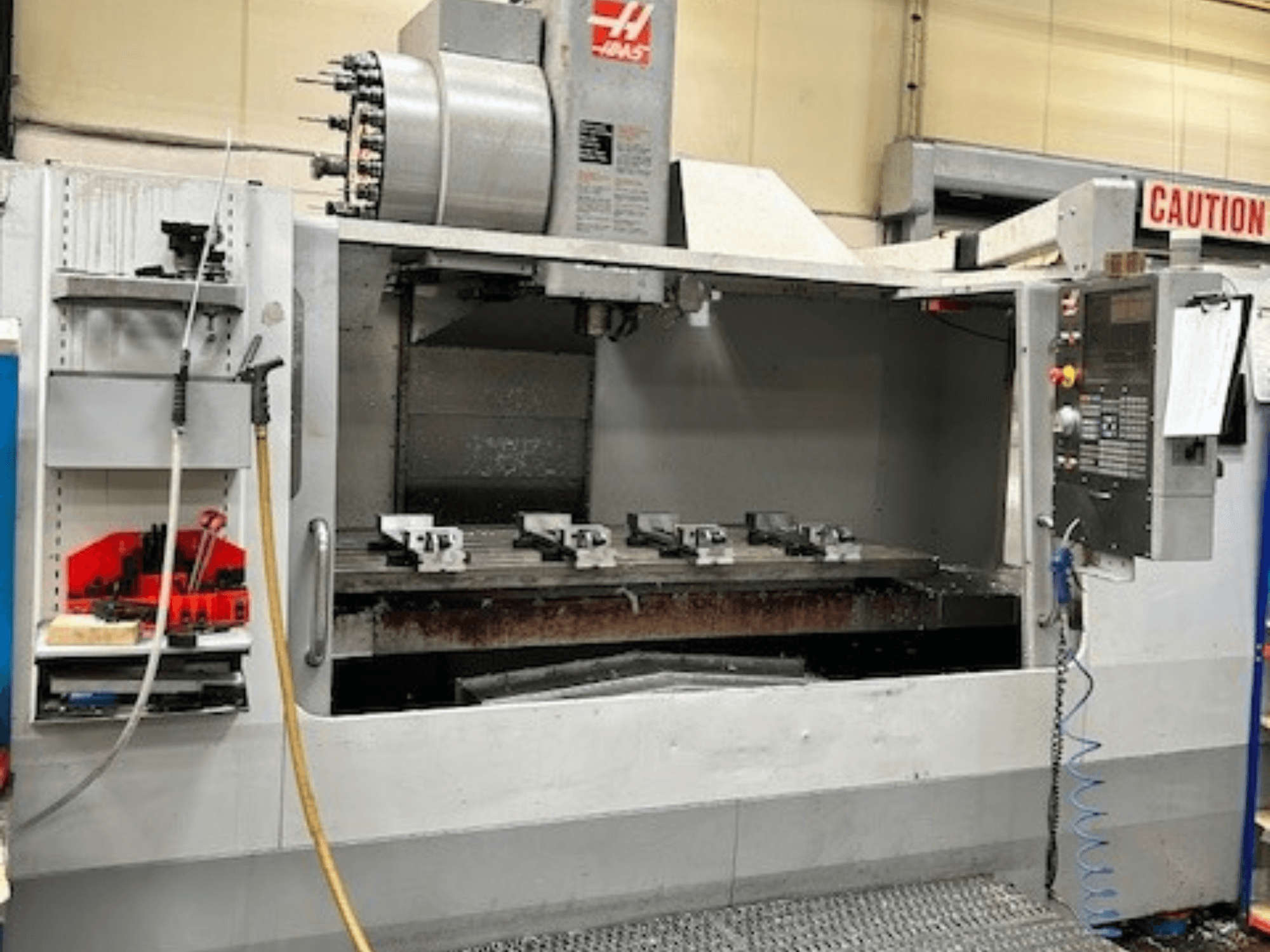 Вертикальний обробний центр HAAS VF-9/40HE, вид спереду, з тримачем інструменту та аксесуарами збоку.