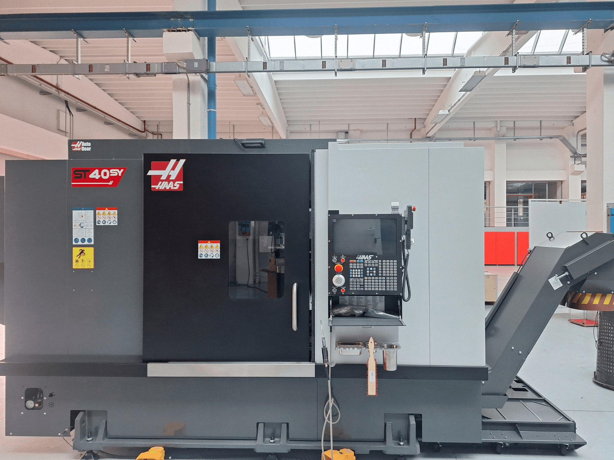 Горизонтальний токарний верстат Haas ST-40SY у боковому ракурсі, на якому видно панель управління та попереджувальні наклейки.