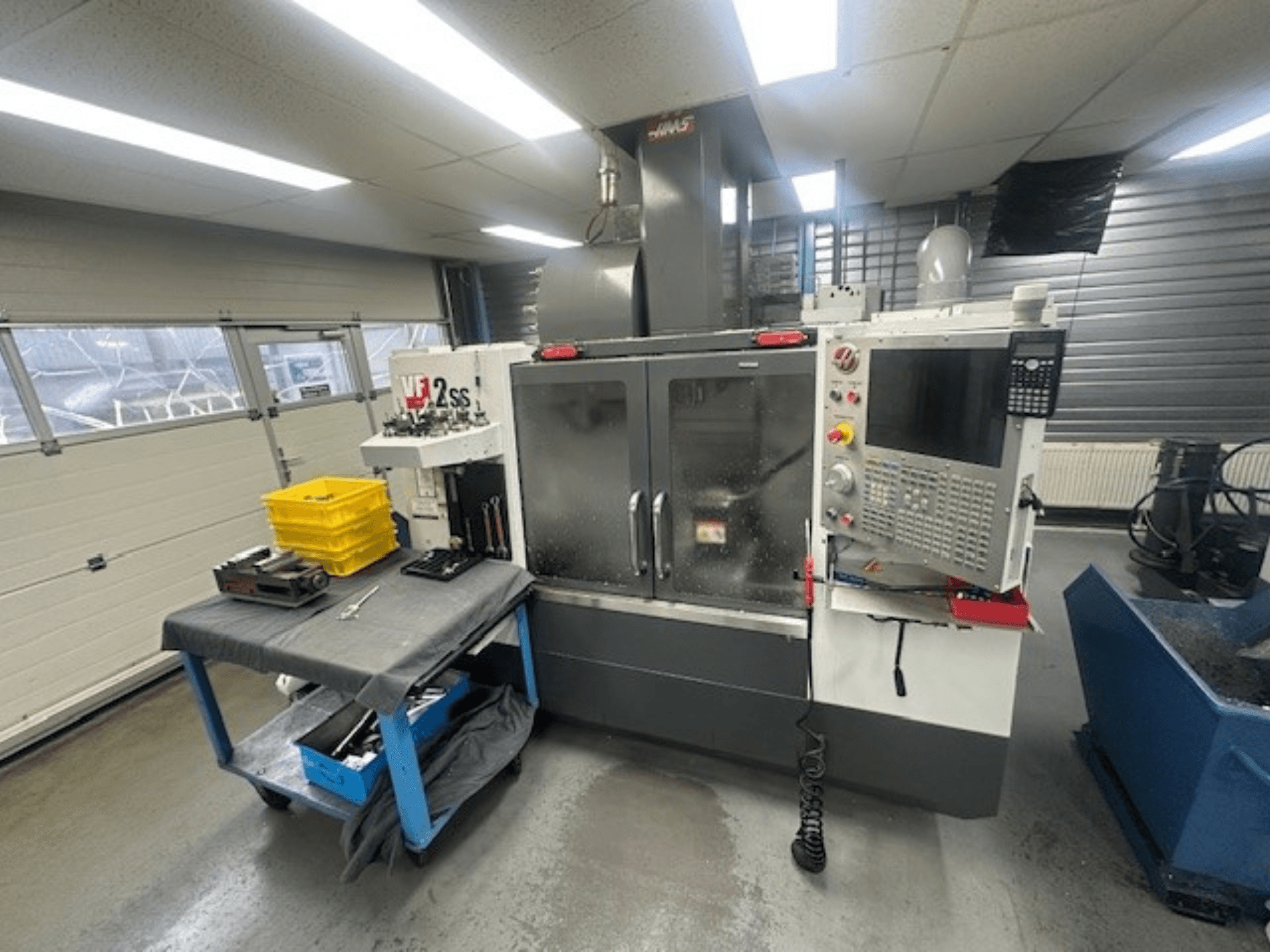 Вид спереду вертикального обробного центру HAAS VF-2SS з панеллю керування, робочим столом та місцем для зберігання інструменту.
