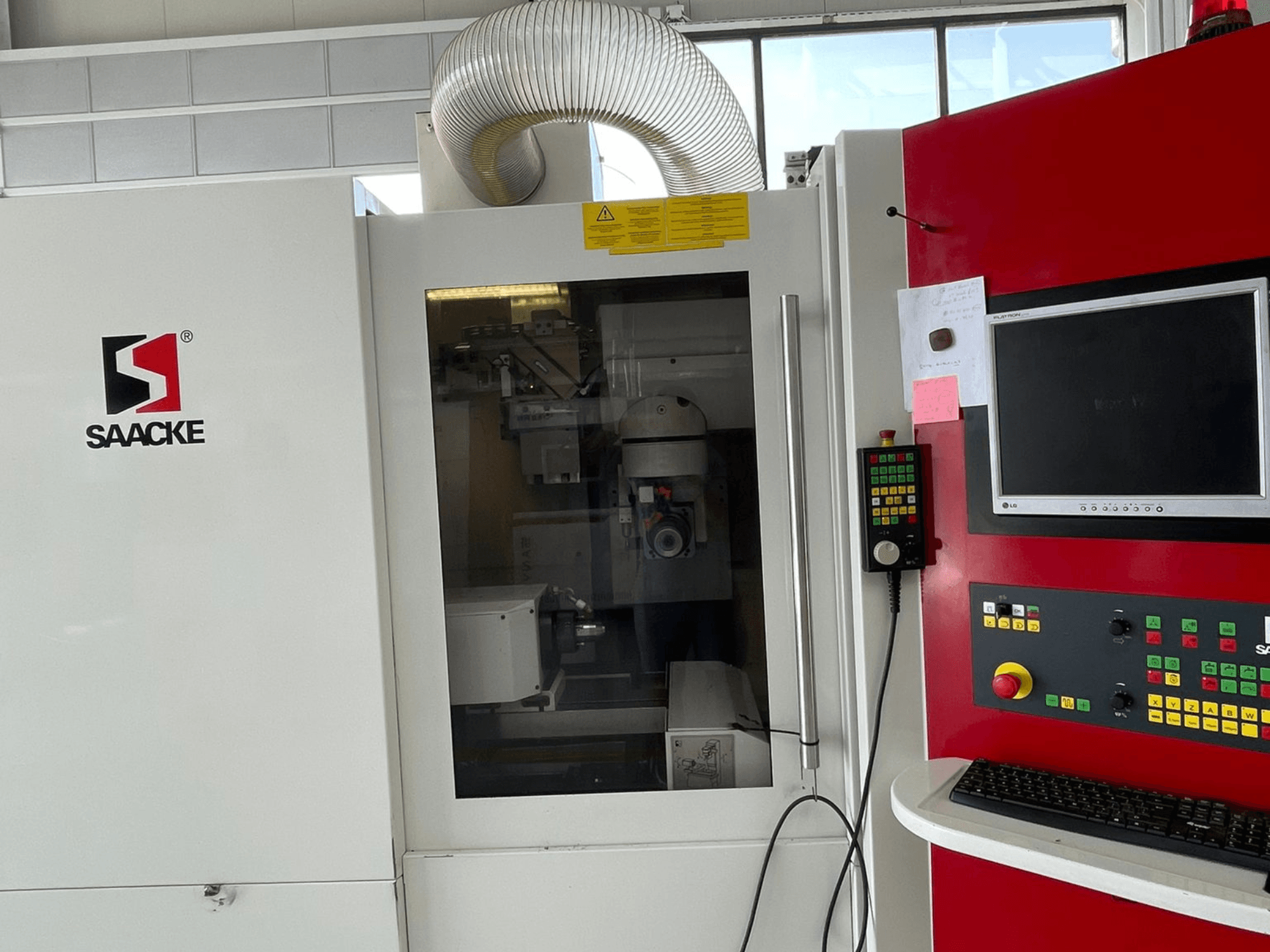 Машина SAACKE в біло-червоному кольорі, вид спереду, має панель управління, монітор і внутрішні деталі, видимі крізь скло.
