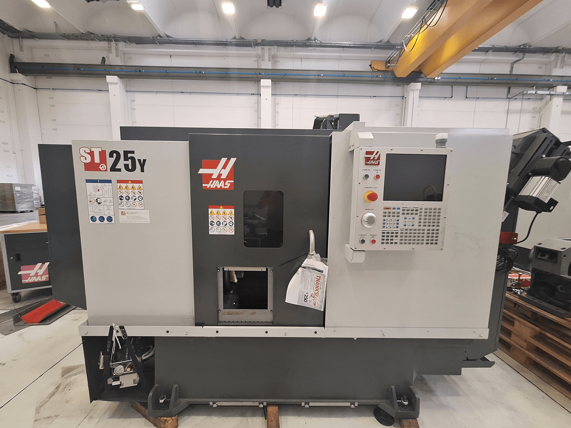 Горизонтальний токарний верстат Haas ST-25Y, вид спереду, з панеллю керування та попереджувальними наклейками. Ідеально підходить для прецизійної обробки.