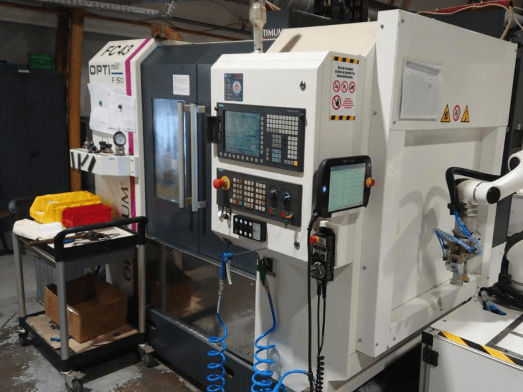 Панель керування фрезерним верстатом OPTIMUM F50 зі шлангами, інструментами та роботизованою рукою в умовах майстерні.