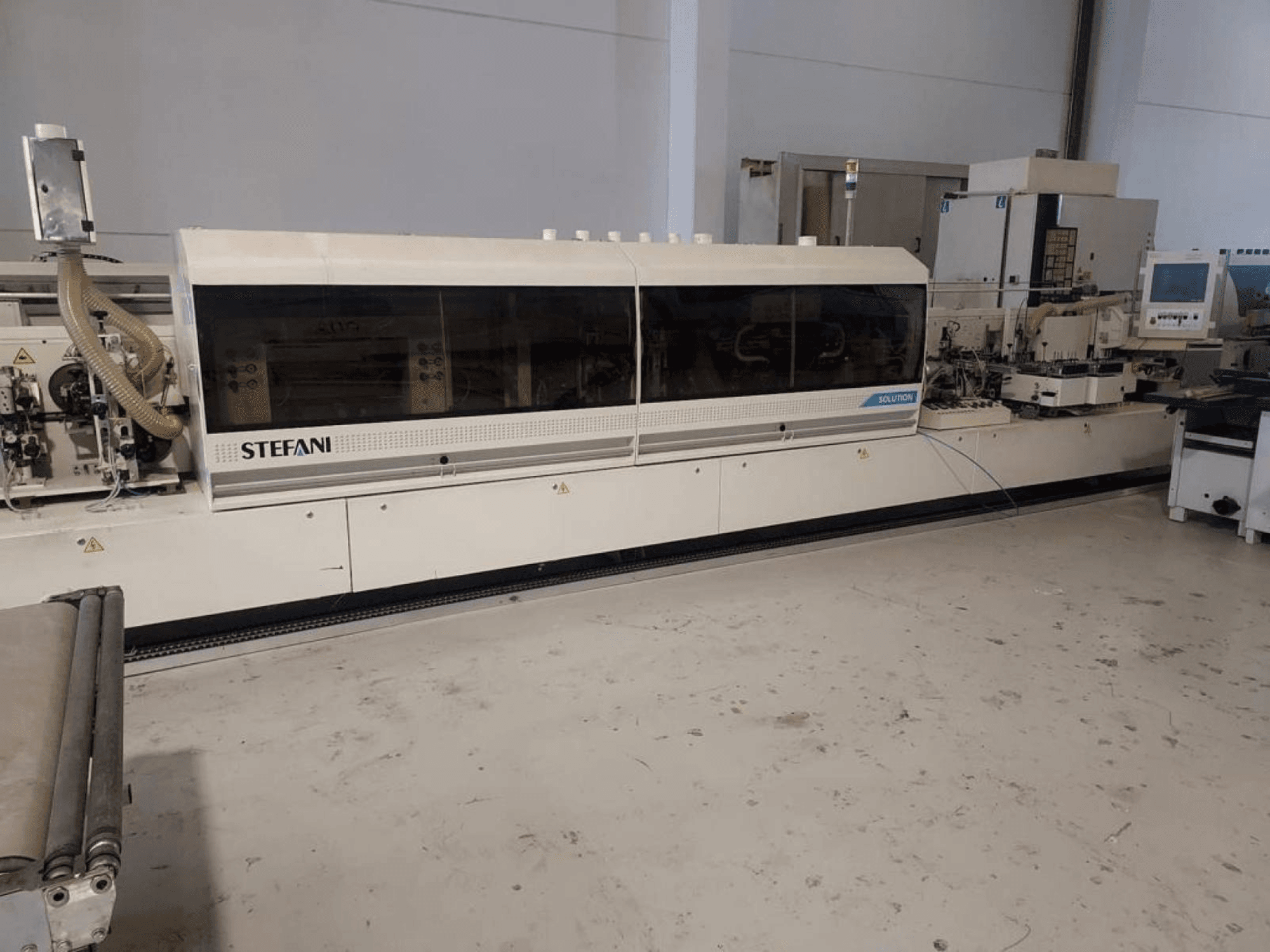 Кромкооблицювальний верстат Stefani Solutions, вид спереду, з видимою системою відсмоктування пилу і панеллю керування, в умовах майстерні.
