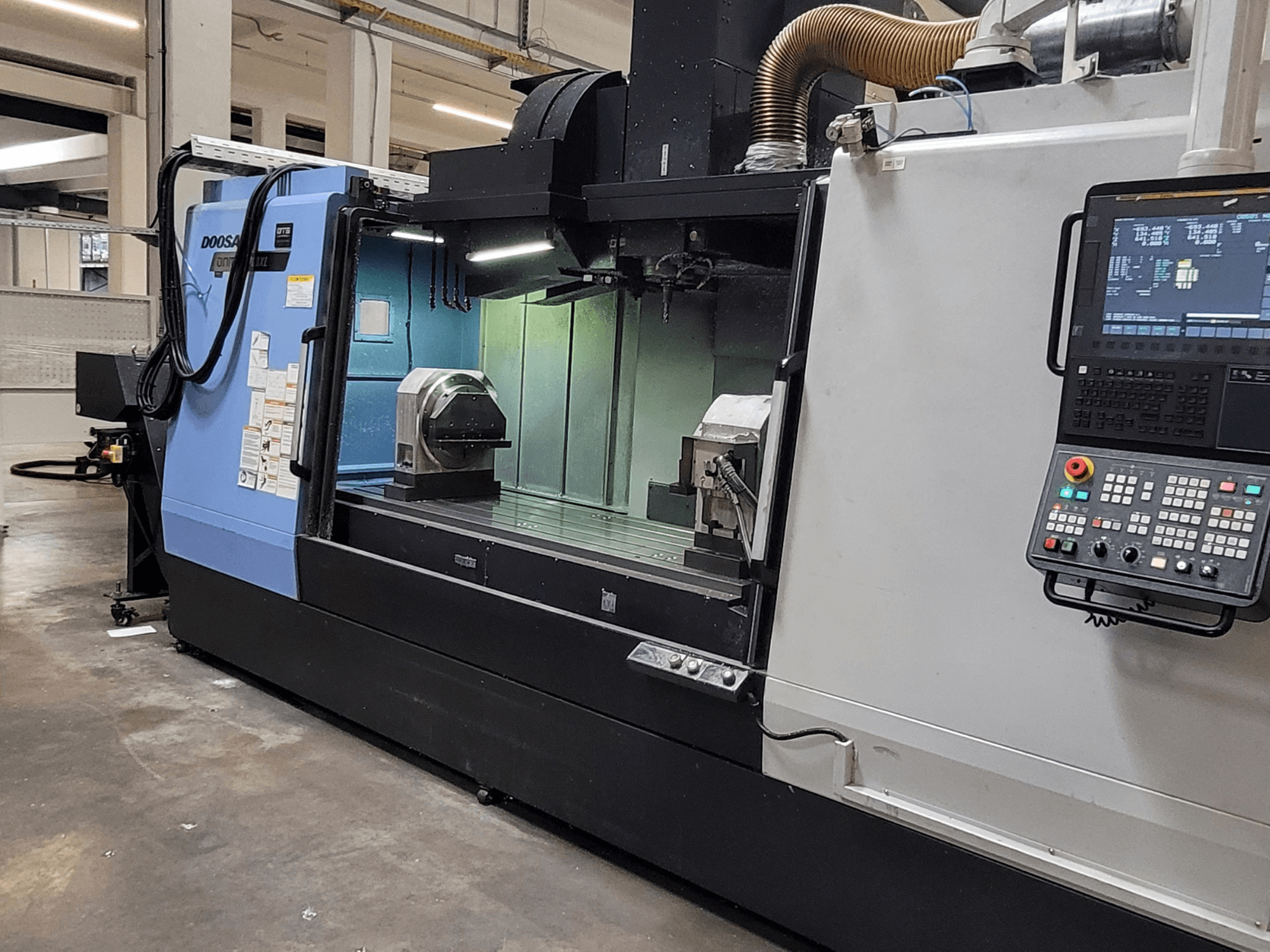 Вертикальний обробний центр DOOSAN DNM 6700 XL, вид спереду, на якому видно панель управління, робочий стіл та зону обробки.