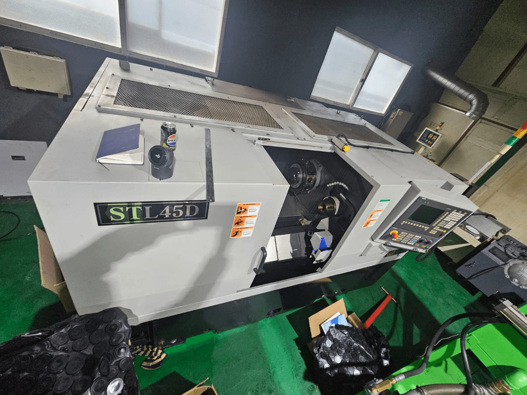 Верстат з ЧПУ STL45D, вид зверху, на якому видно панель керування, циліндричну частину, ноутбук і банку зверху.