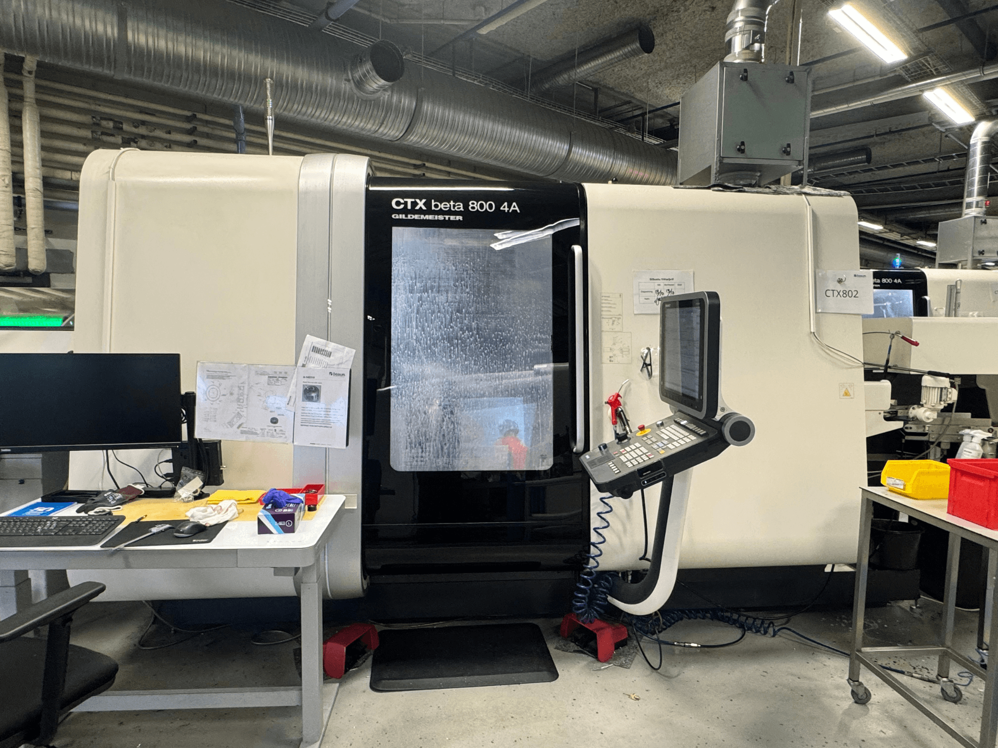 Верстат з ЧПК CTX beta 800 4A в майстерні, вид збоку: панель керування та робочий простір, захаращений інструментами та документами.