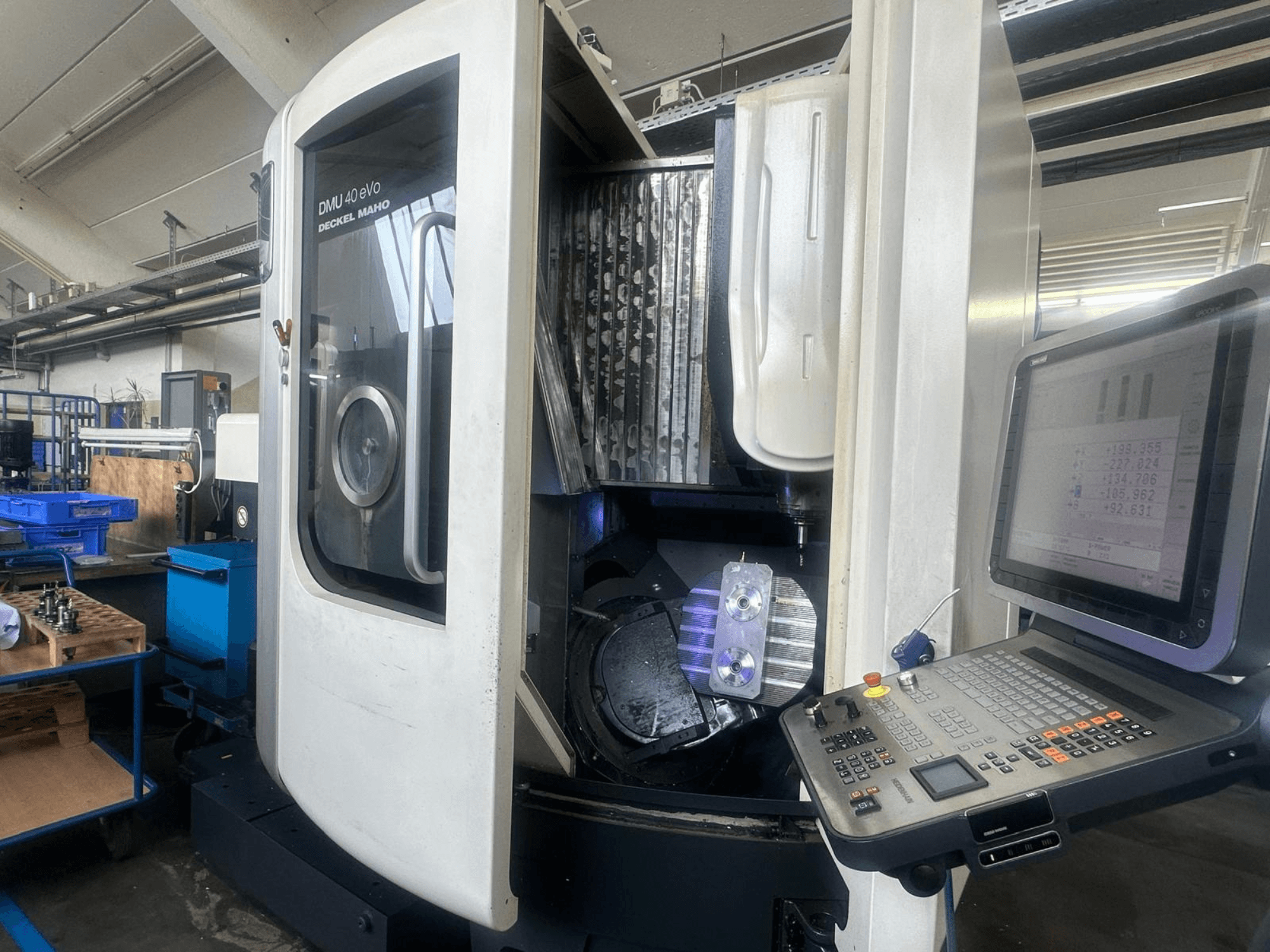 Фрезерний верстат DMU 40 eVo від Deckel Maho в майстерні, вид спереду, з панеллю керування та металевою заготовкою в шпинделі.