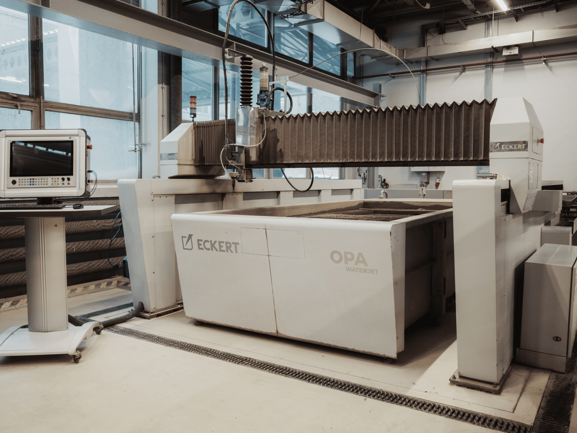 Різальний верстат ECKERT OPAL WATERJET у цеху, зображений спереду, поруч із консоллю управління.