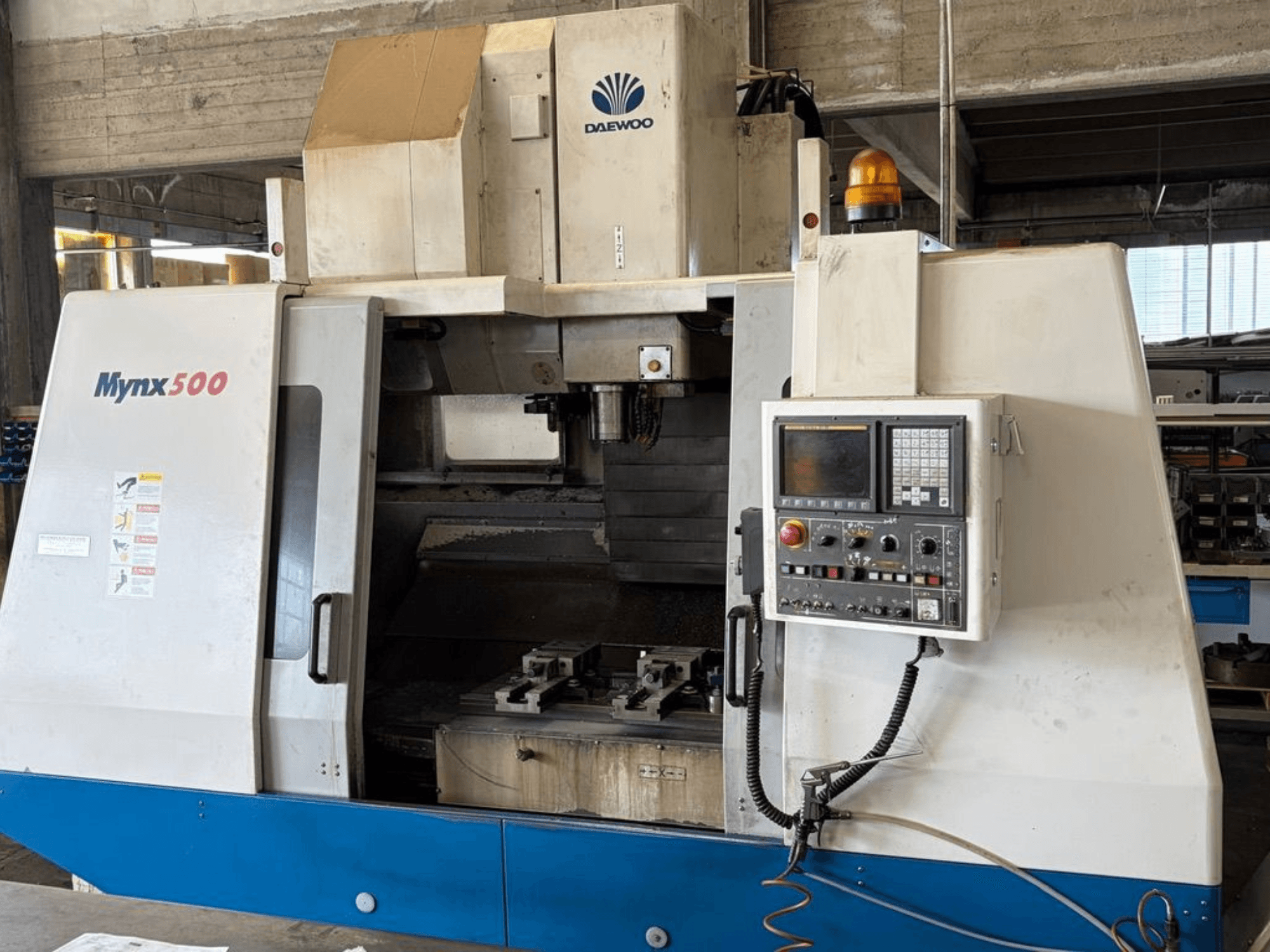 Вертикальний обробний центр DAEWOO Mynx 500, зображений у фронтальному ракурсі, з панеллю керування та тримачем інструменту всередині.
